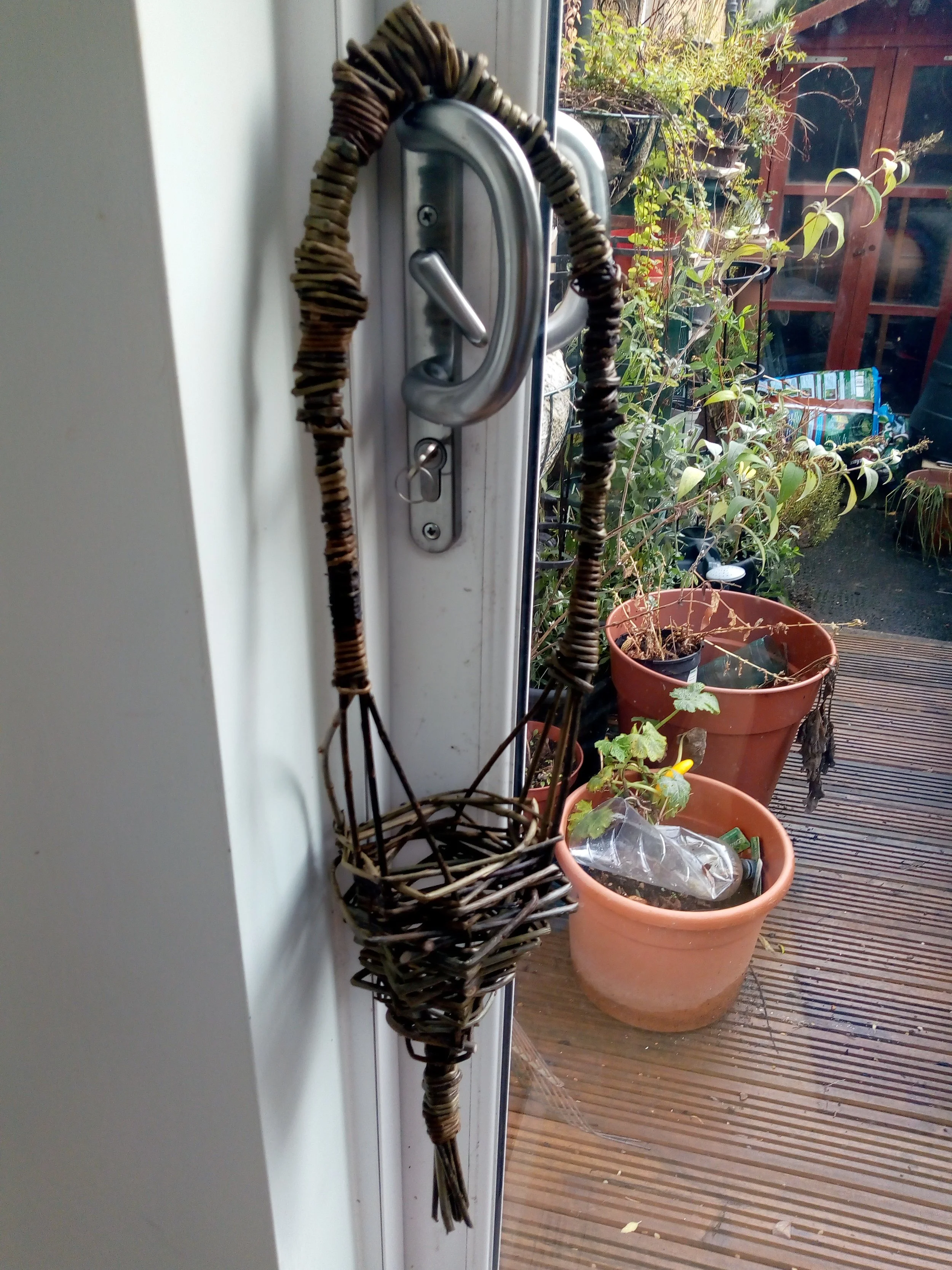 A woven willow wicker basket hanging from a hook on a door handle created by awaywithwillow.com