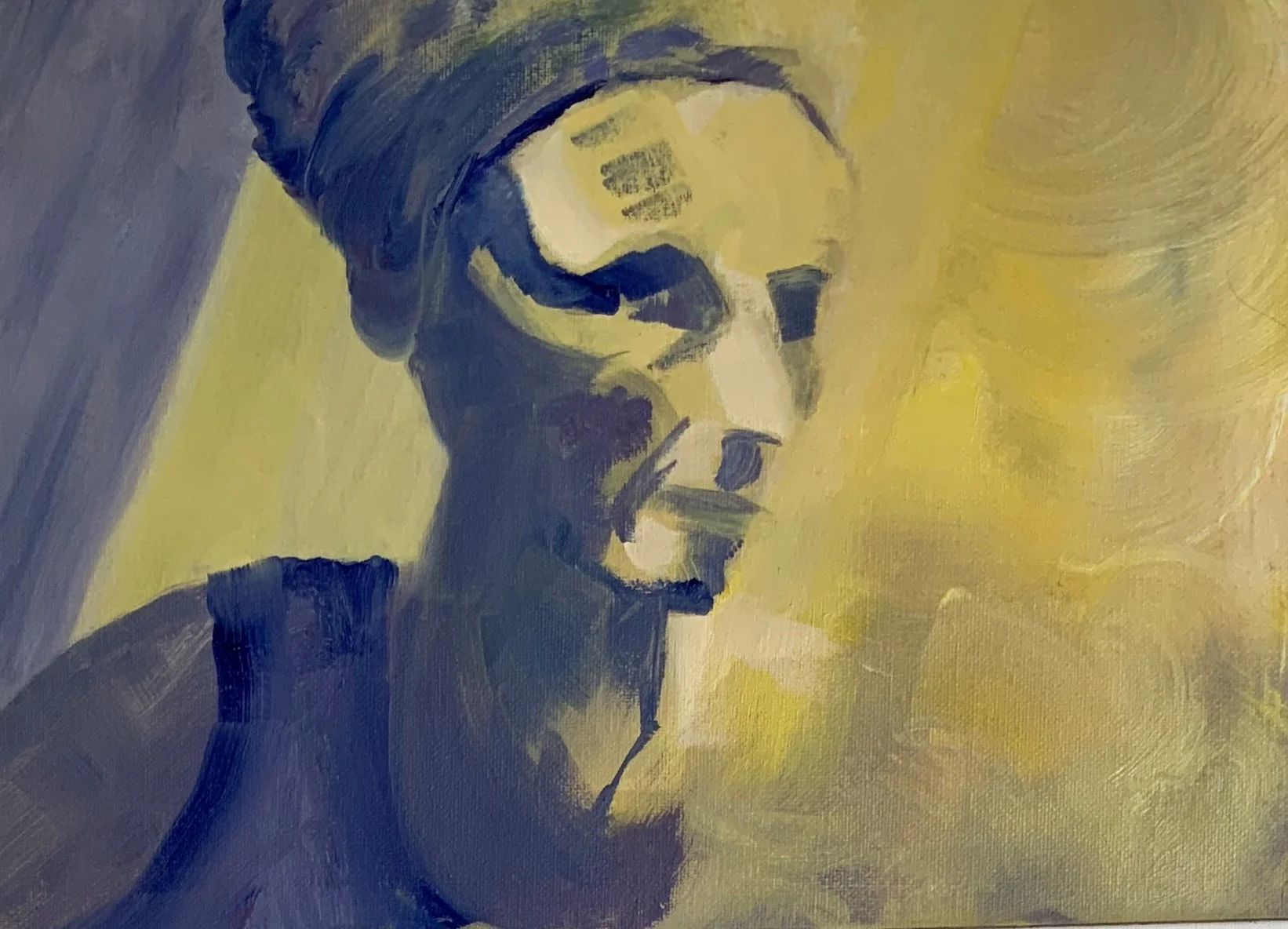 Self portrait, oil on board, 2021. Navy blue depicts the shadows and shades of yellow form the background and highlights. My face. shaped by broad, angular strokes, gazes to my left with an expression of serious intent.