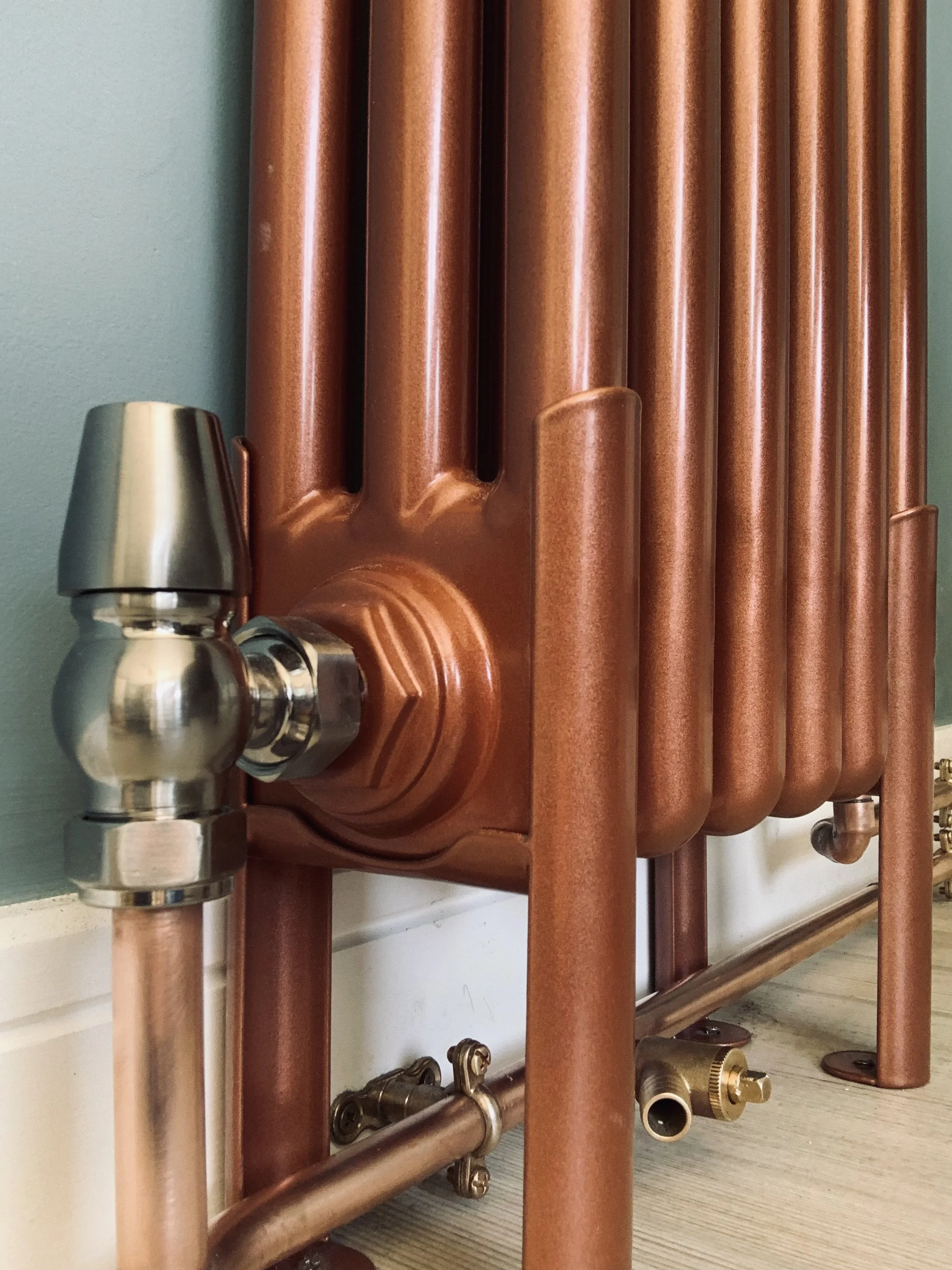 Close-up of a copper radiator with a metallic pipe and valve fitting.