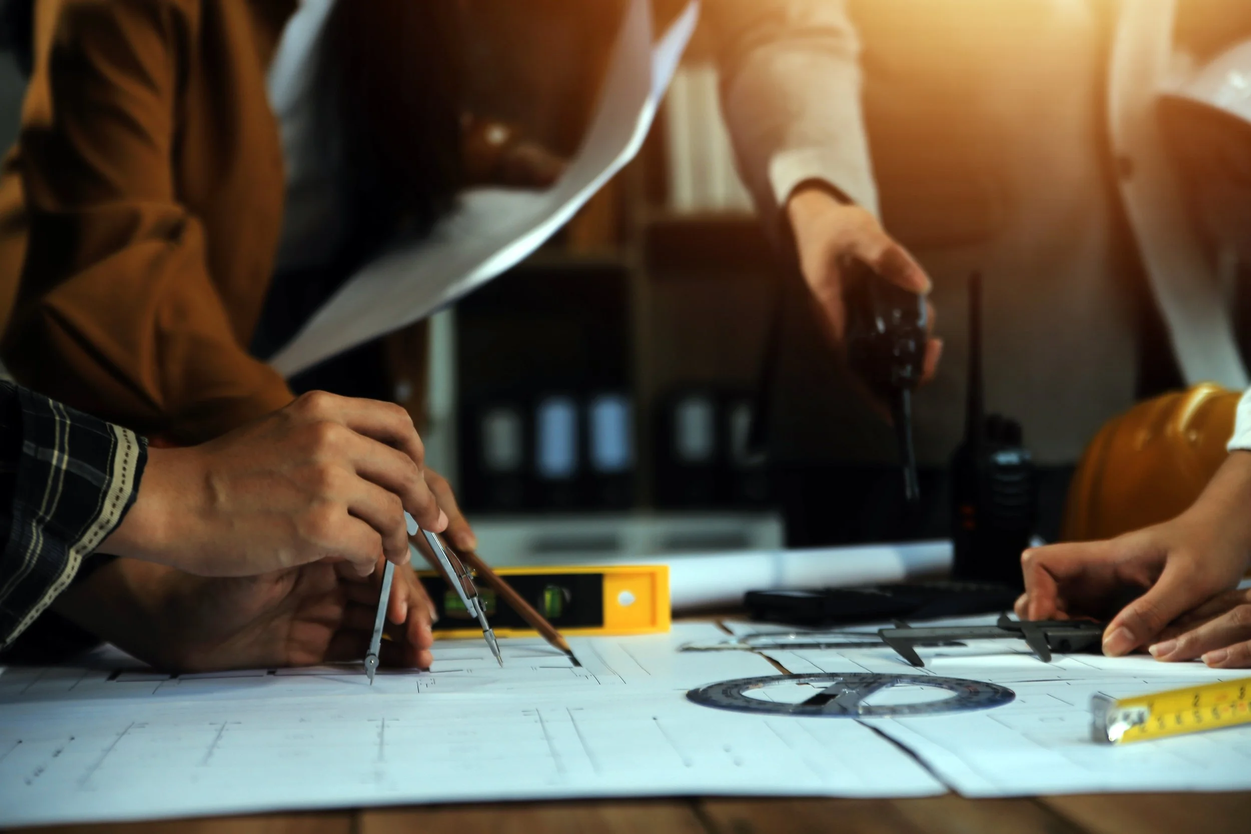Team of engineers collaborating on construction plans with technical drawing tools and two-way radio for site coordination