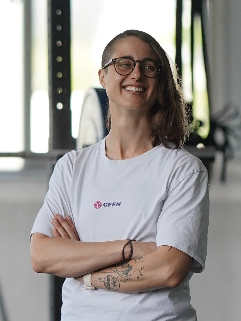 Yvonne, Coach bei CrossFit Friedrichshafen, im weißen CFFN-Shirt mit verschränkten Armen in der Box