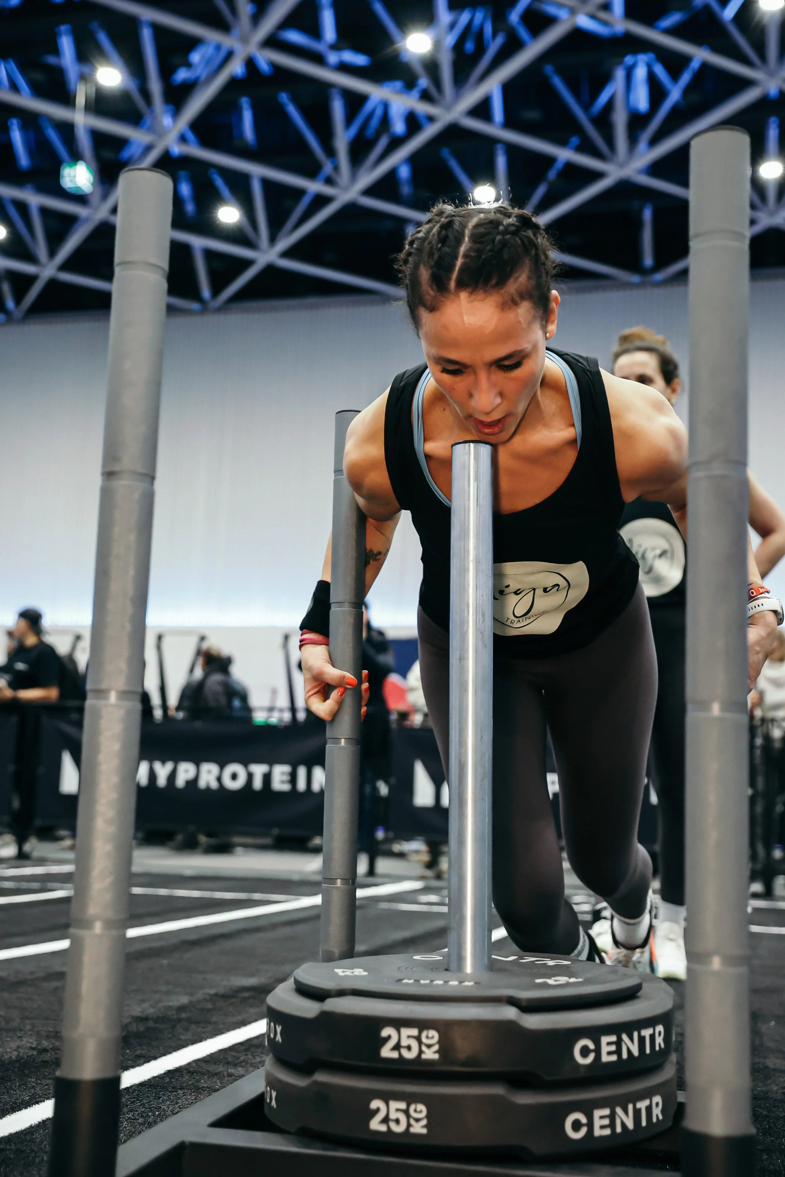 Frau beim Krafttraining mit Gewichtsscheiben in einem Fitnessstudio.