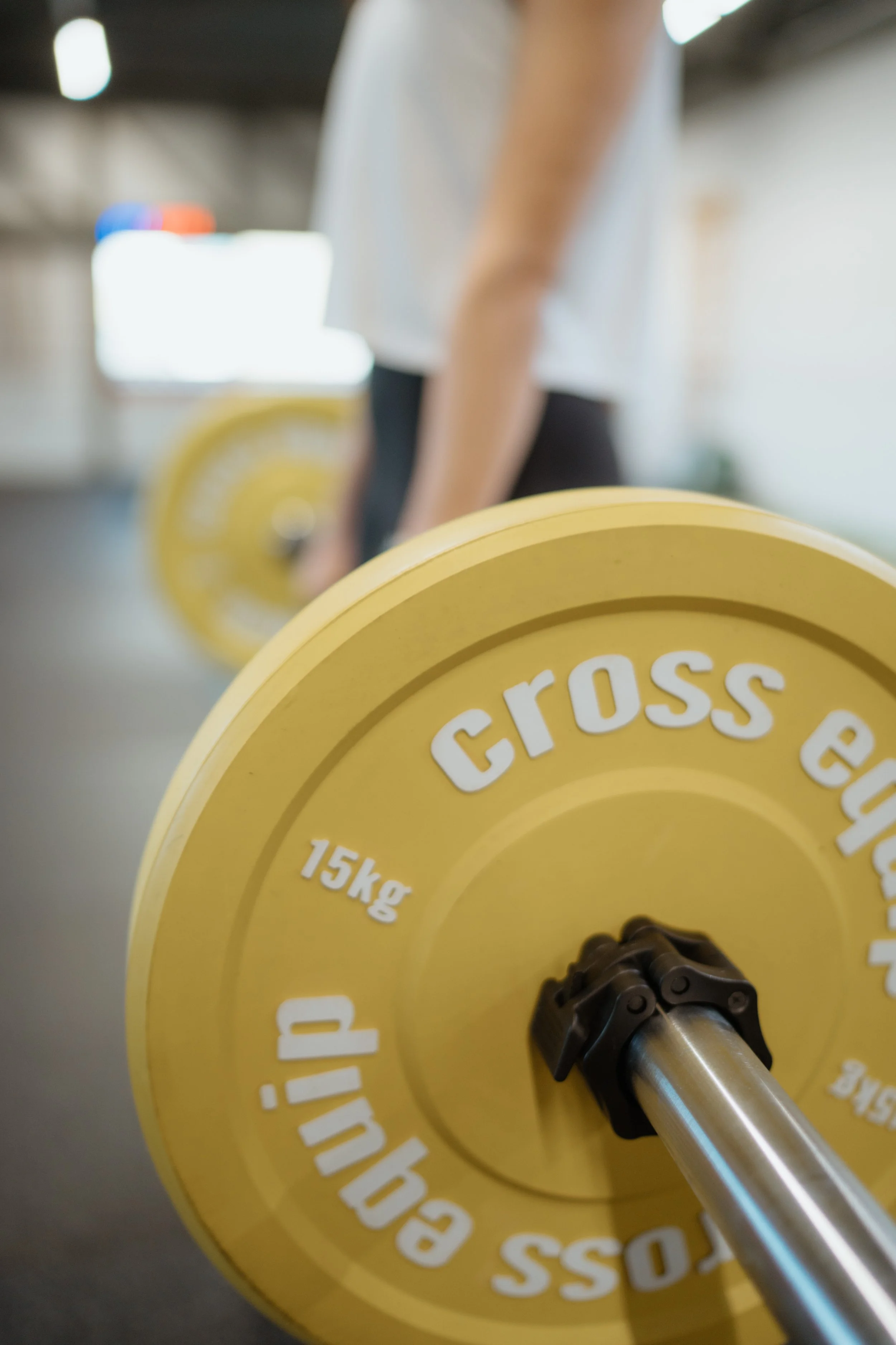 Nahaufnahme einer gelben Hantel mit der Beschriftung 15kg auf einer Fitness- oder Krafttrainingshalle