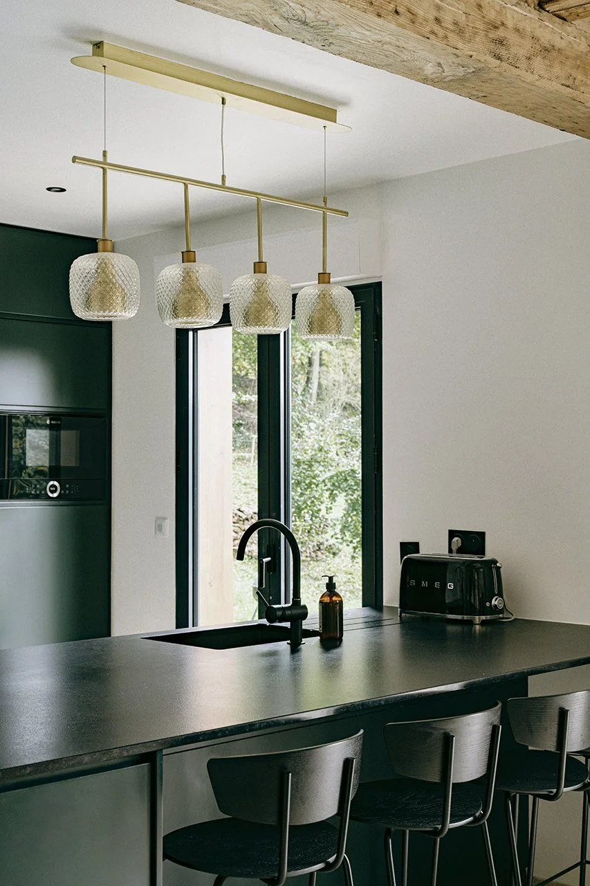 la suspension en laiton contraste avec la cuisine vert foncé et noir