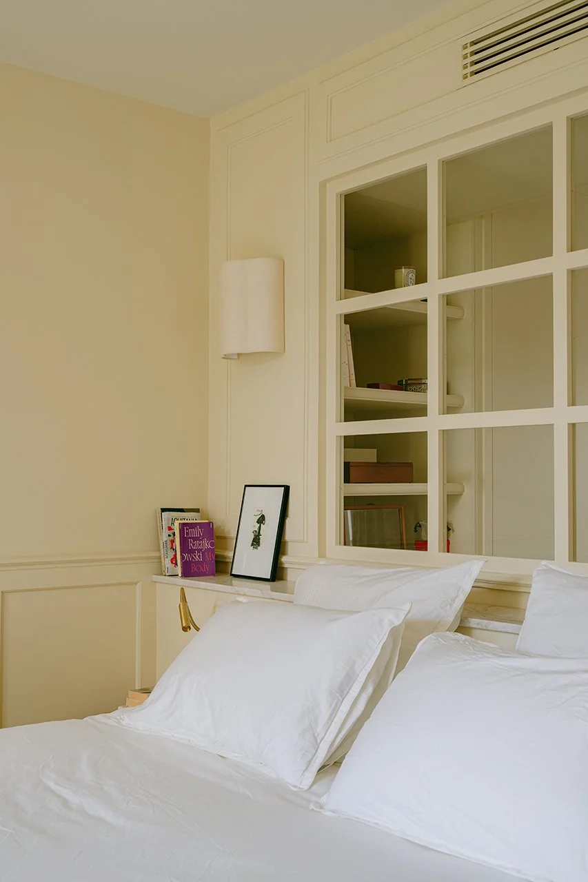 Une verrière en tête de lit dans la chambre parentale. La couleur beige recouvre les murs et le plafond pour apporter de la douceur et de la chaleur à l'ensemble