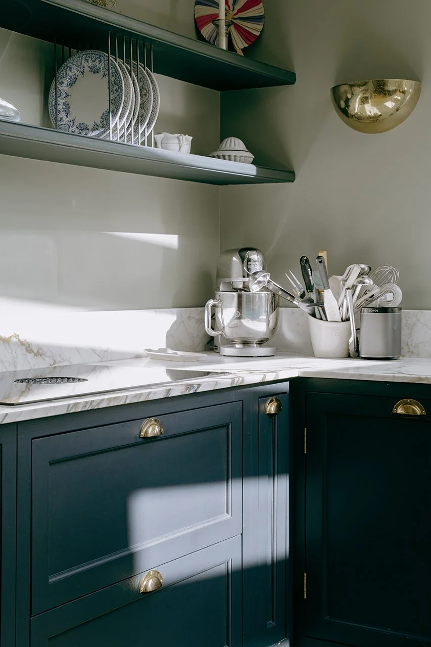 détails de la cuisine, les meubles moulurés bleus foncé sont réhaussés grâce à un plan de travail en marbre. Les appliques et boutons de meubles en laiton réveillent l'ensemble