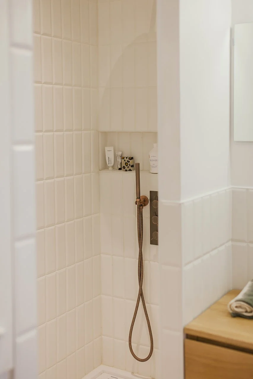 la douche à l'italienne se pare d'une faïence blanche qui contraste avec la robinetterie en coloris bronze.