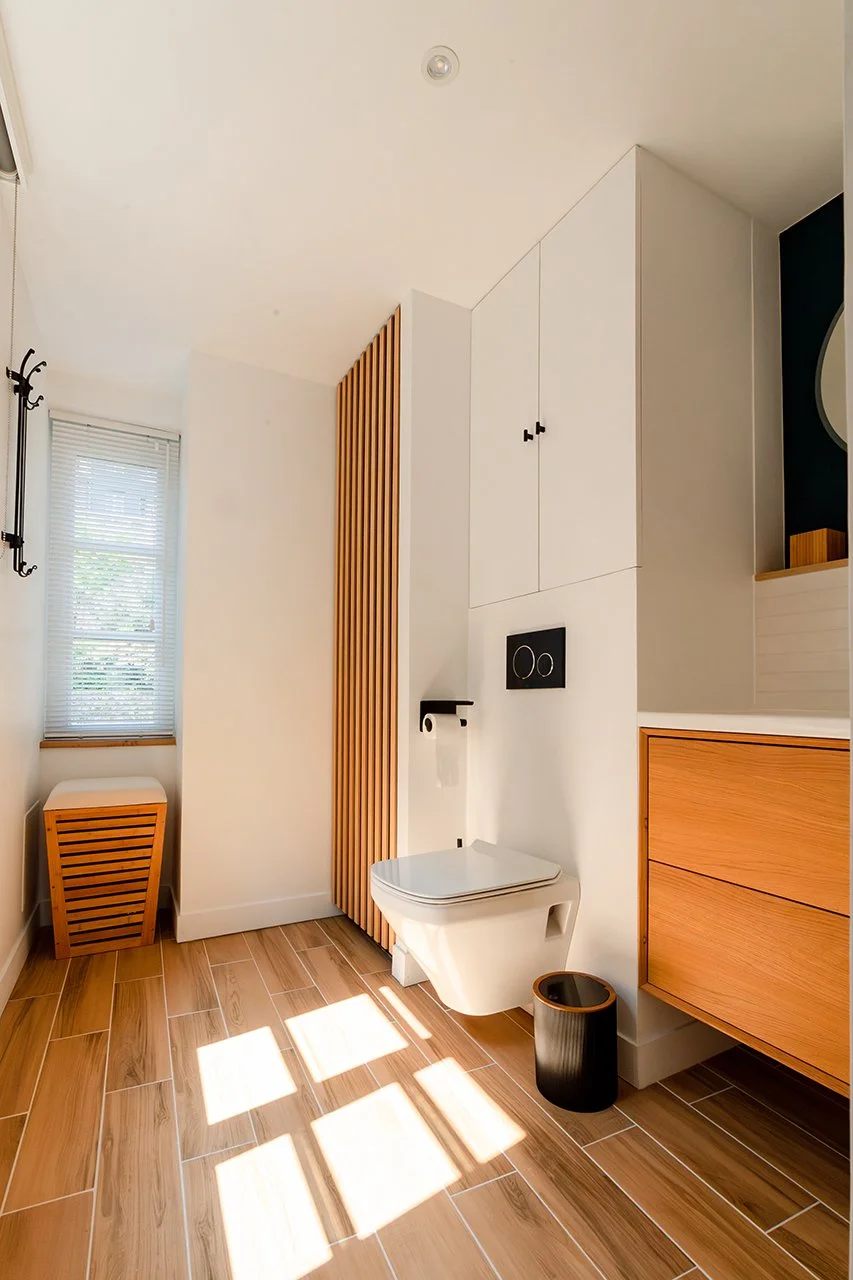 le bois est également très présent dans la salle de bain par le sol en carrelage effet parquet, le meuble en bois massif et les tasseaux du placards qui font échos à ceux du dressing d'entrée.