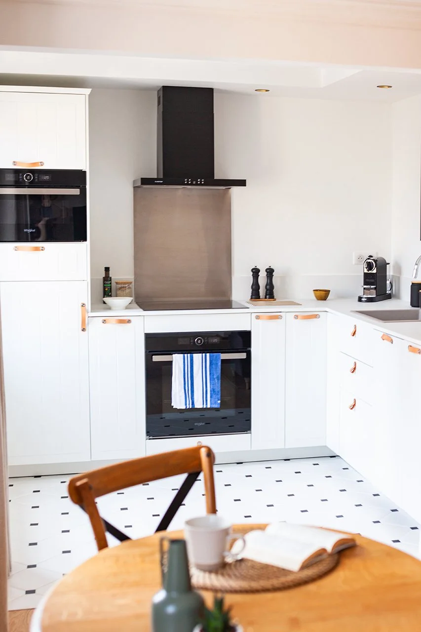 la cuisine revêt un esprit campagne avec ses façades moulurées, son sol en octogone et cabochons et ses poignées en cuir.