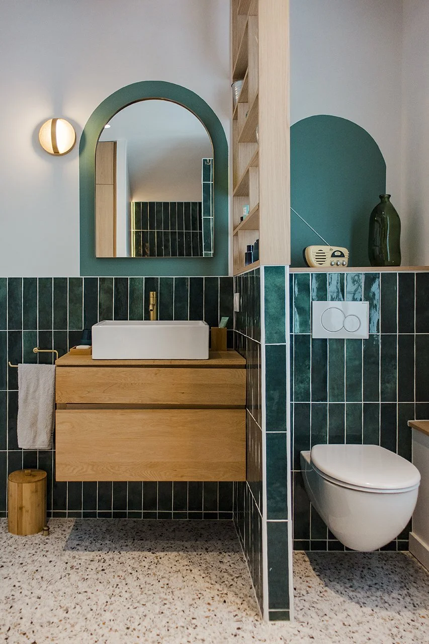 les wc et le meuble vasque sont séparés par un muret surmonté d'un claustra bois qui sert également de rangement d'appoint pour les produits de beauté.