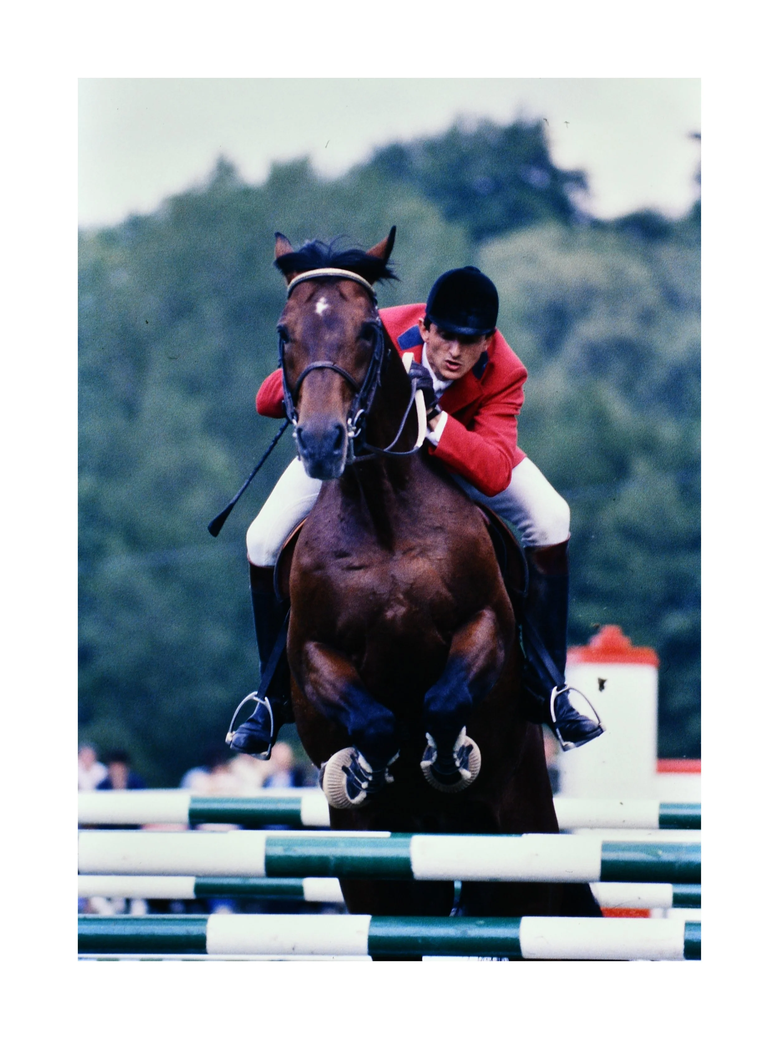 Photographie argentique d’un saut d’obstacle lors d’un concours hippique en 1985, cavalier en veste rouge franchissant une barre, archive de Didier Arrès.