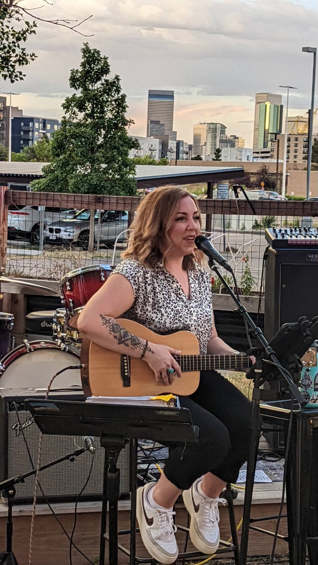 Singer/Songwriter Katie Quick plays an outdoor house concert holding a guitar.