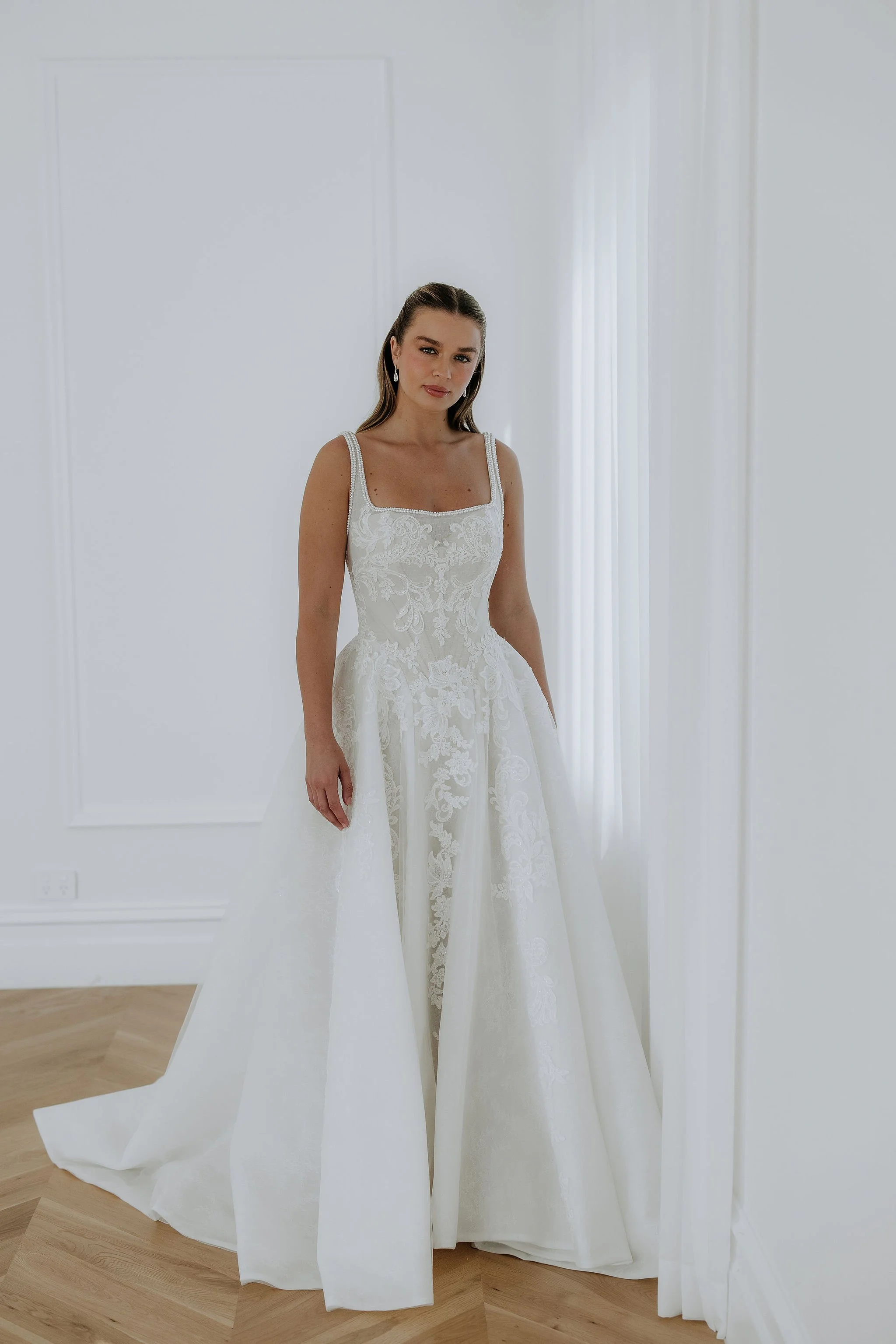 Ornella by Kelly in a modern wedding dress with square neckline and lace and pearl details. Full A line skirt brings the drama.