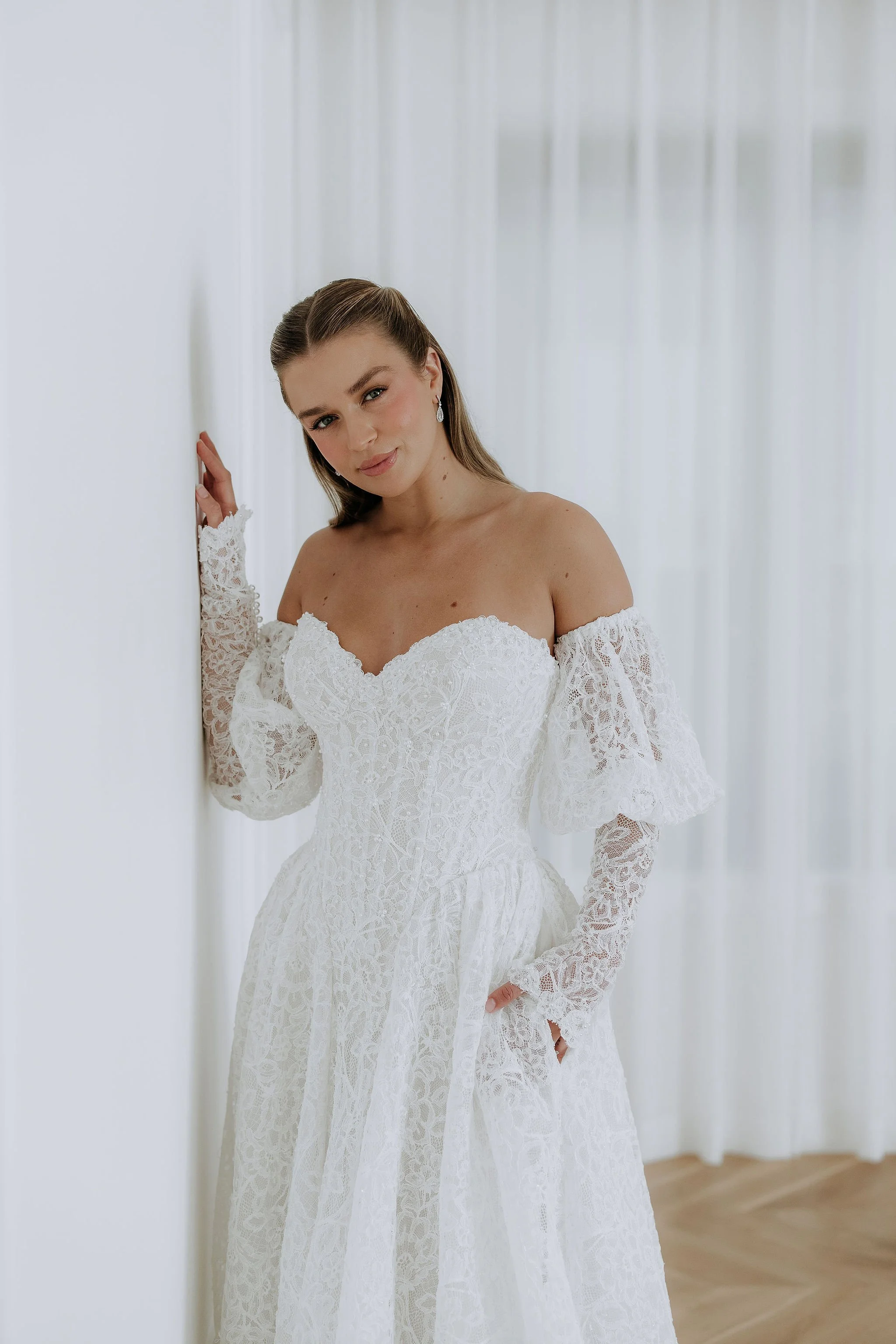 Lottie by Kelly Lin is soft lace wedding dress with lace sleeves. Strapless, boned bodice in nude or ivory.
