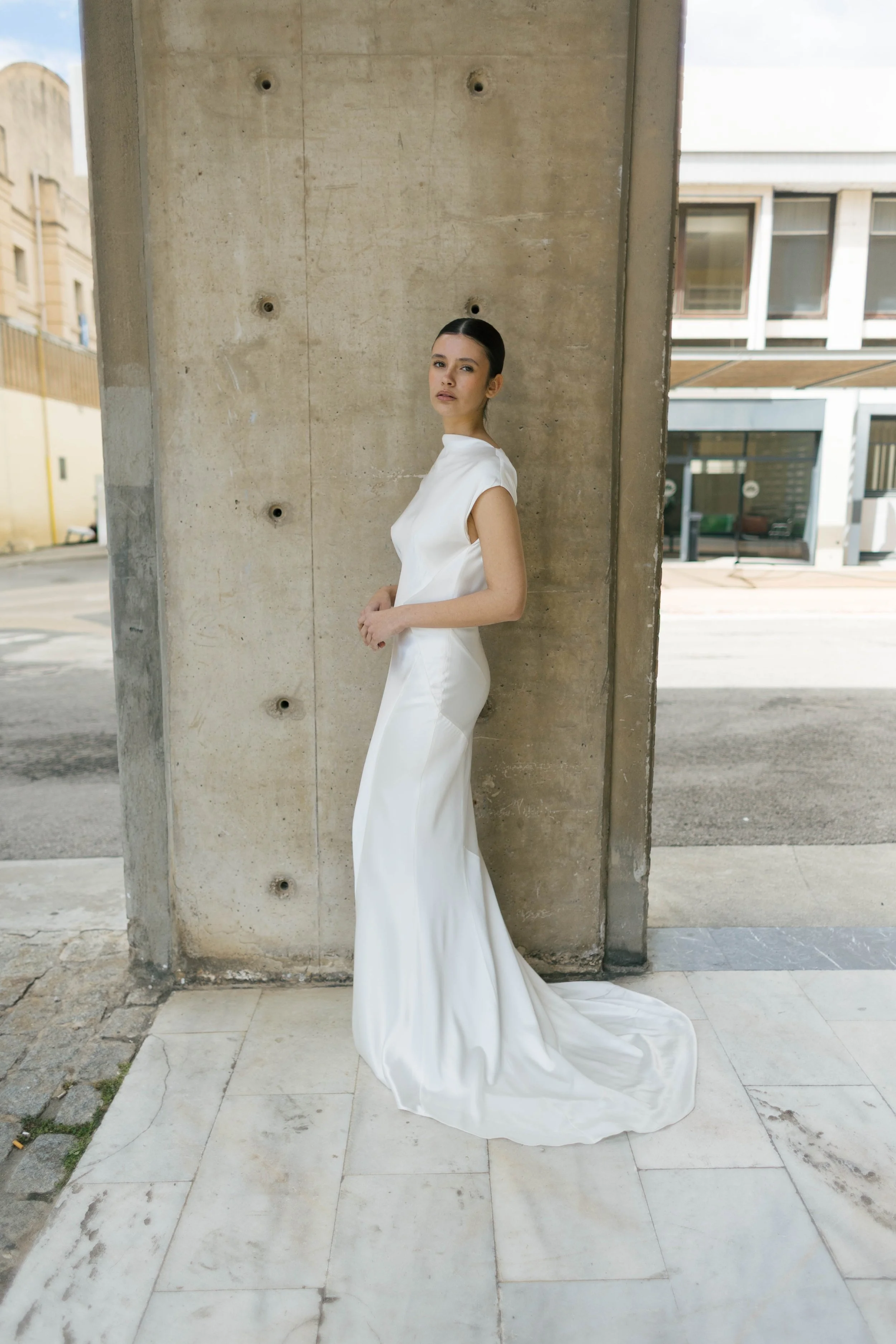 Beatrice Dress by Rolling in Roses – minimalist satin bridal gown with high cowl neckline, open back, angular darts, and detachable wrist loop, crafted from sustainable vegan satin and organic bamboo, available at Lyra Bridal Studio, UK