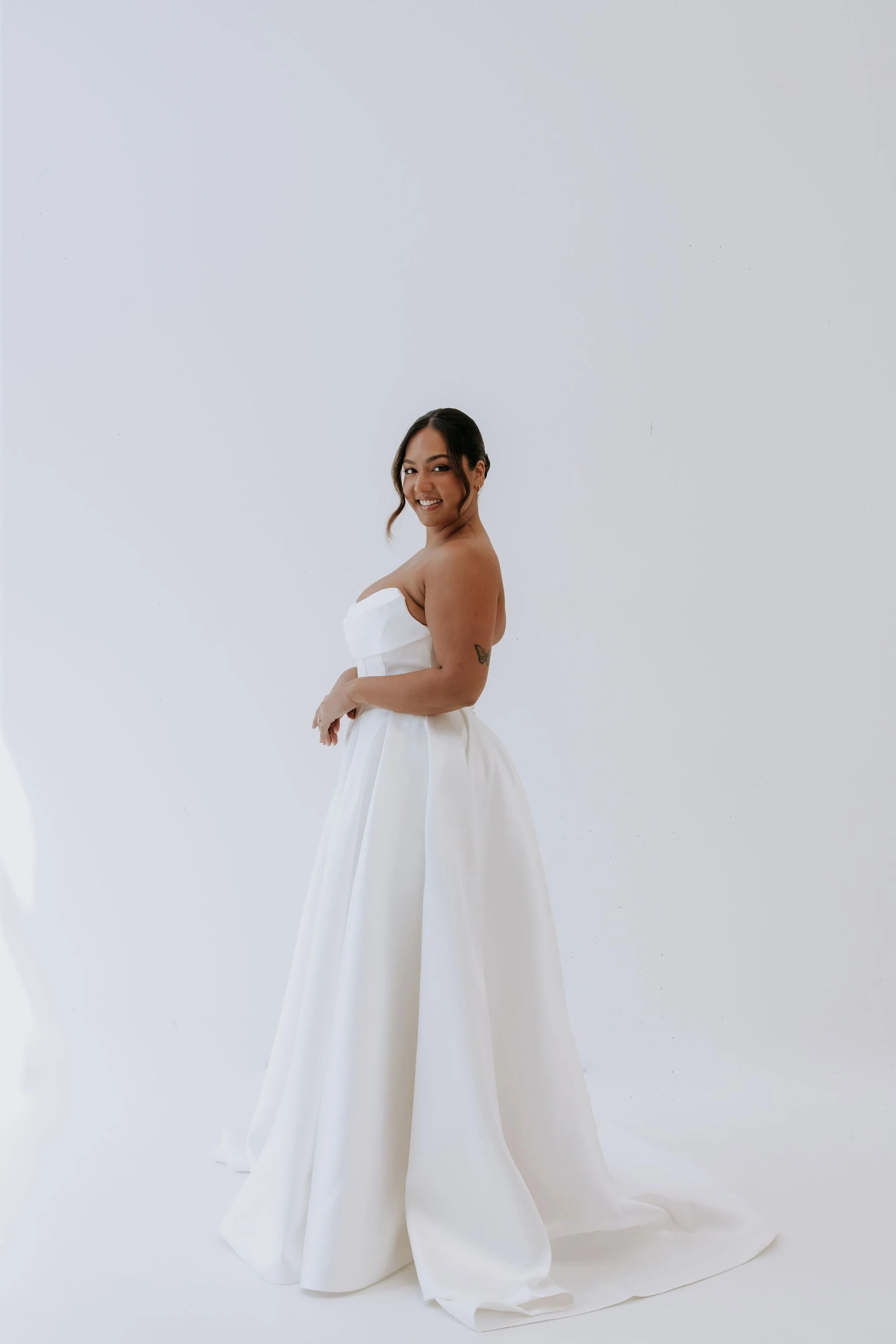 The Abbey Dress is by Australian designer Kelly Lin. A strapless gown with optional off the shoulder sleeves. Made from Mikado fabric with a Basque waist. Available to try at our Salisbury Wedding Studio.