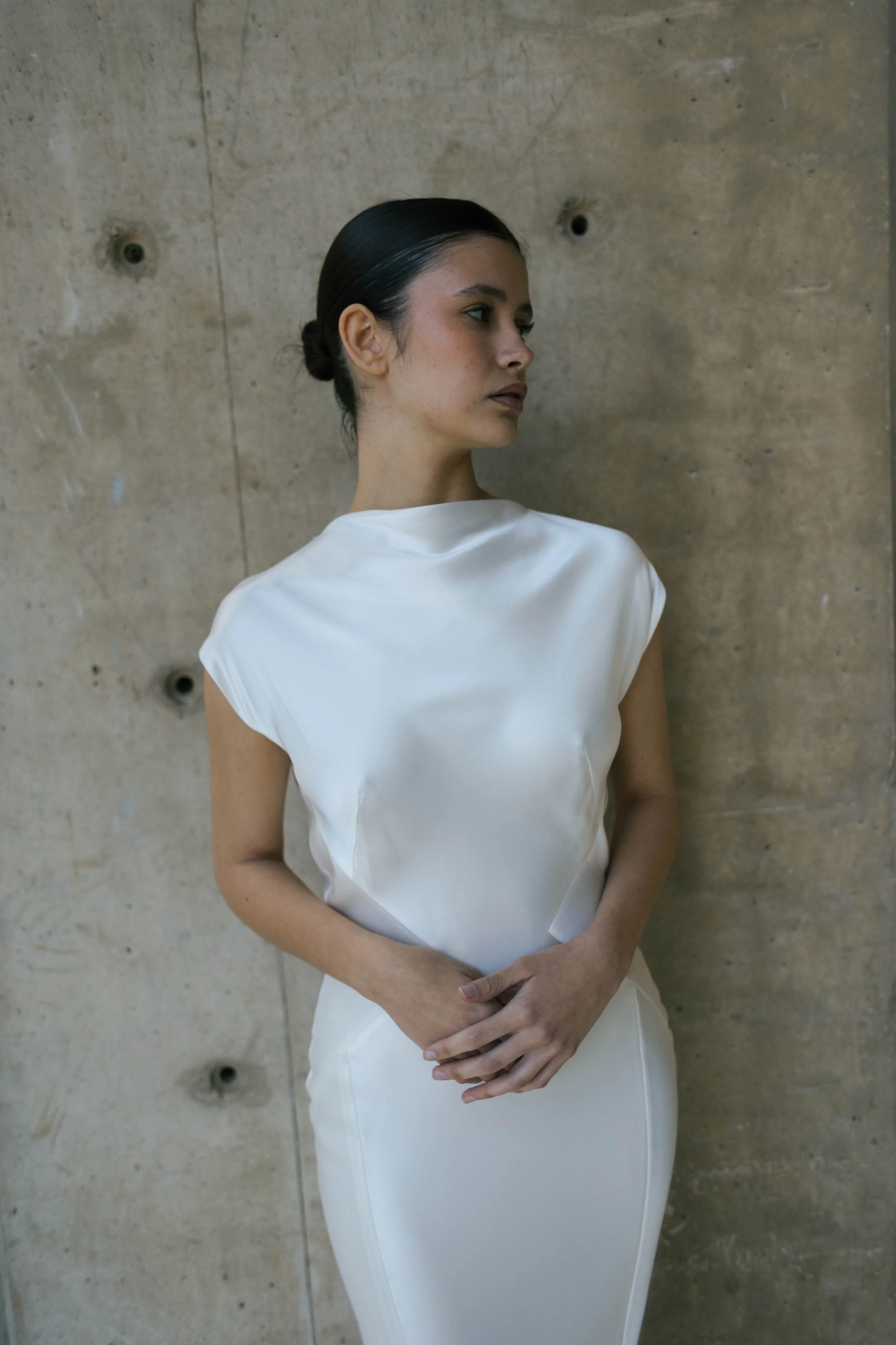 Beatrice Dress by Rolling in Roses – minimalist satin bridal gown with high cowl neckline, open back, angular darts, and detachable wrist loop, crafted from sustainable vegan satin and organic bamboo, available at Lyra Bridal Studio, UK