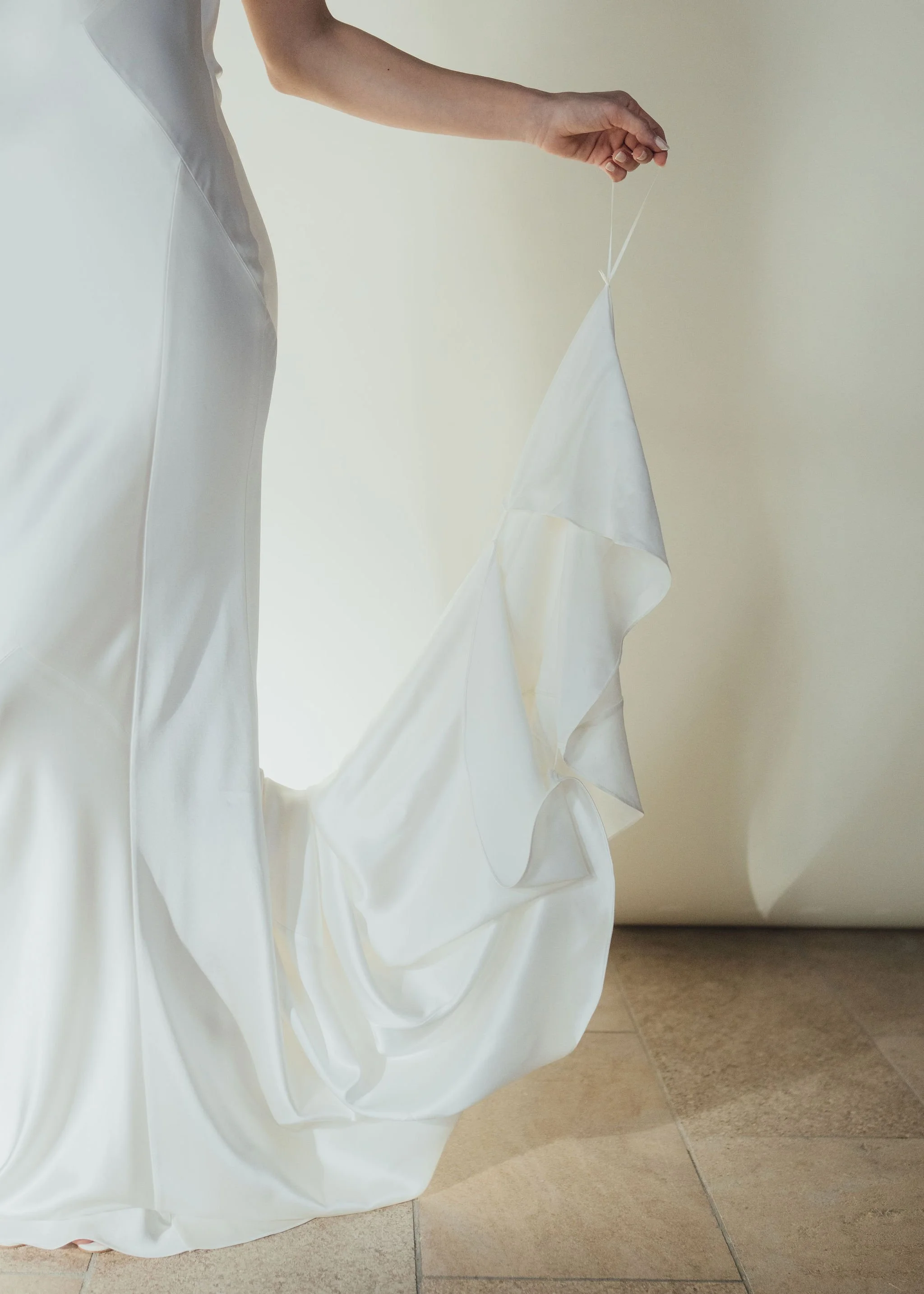 Beatrice Dress by Rolling in Roses – minimalist satin bridal gown with high cowl neckline, open back, angular darts, and detachable wrist loop, crafted from sustainable vegan satin and organic bamboo, available at Lyra Bridal Studio, UK