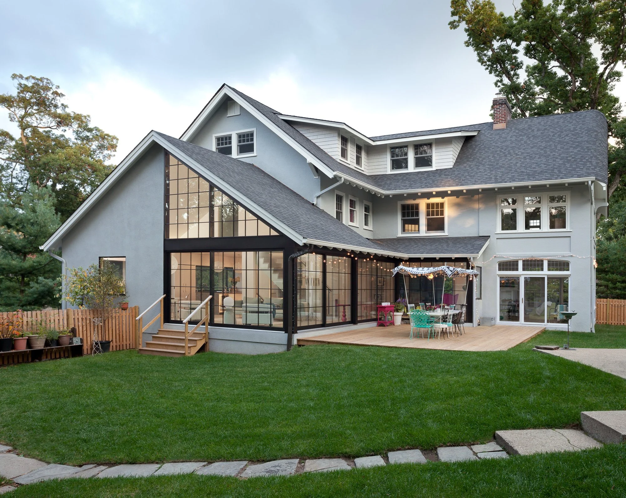 "Traditional English stucco manor home with bold contemporary modern addition featuring floor-to-ceiling steel frame curtain wall windows and outdoor deck — luxury renovation Montclair NJ"