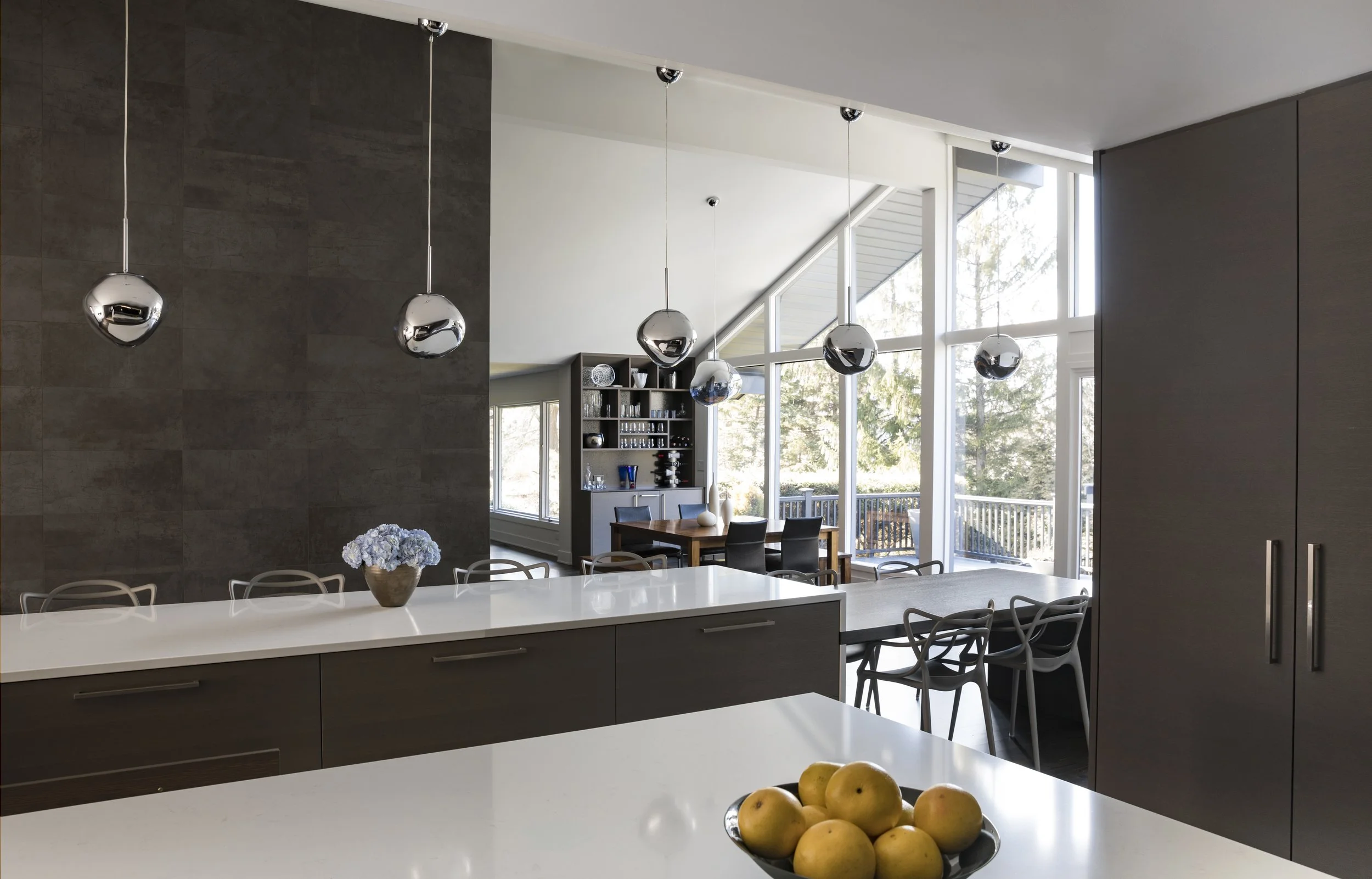 Architectural kitchen view highlighting a custom mirrored backsplash that reflects cathedral windows and an open-concept layout in a high-end residential renovation.