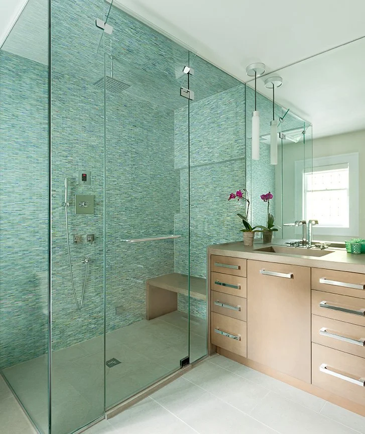 Luxury master bathroom renovation in traditional English stucco home with floor-to-ceiling aqua glass mosaic tile walk-in shower, built-in bench, rain shower head, and custom maple vanity — Montclair NJ