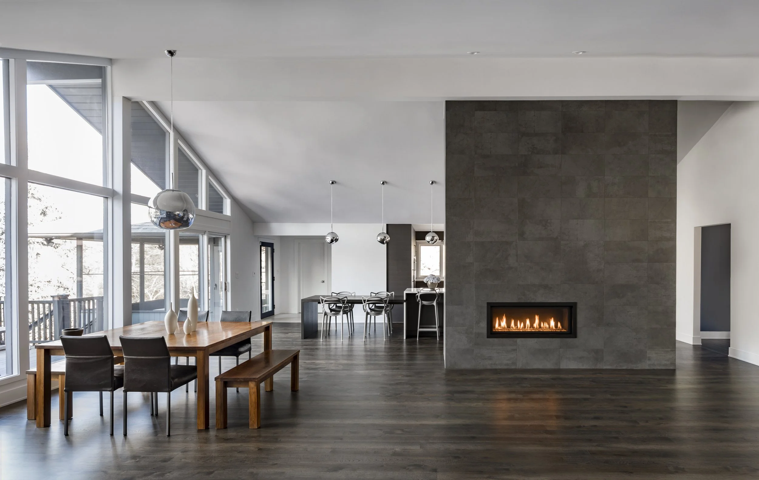 Floor-to-ceiling textured stone tile fireplace wall in an open-concept luxury home renovation. Contemporary residential interior architecture serving Montclair NJ and Denver CO.