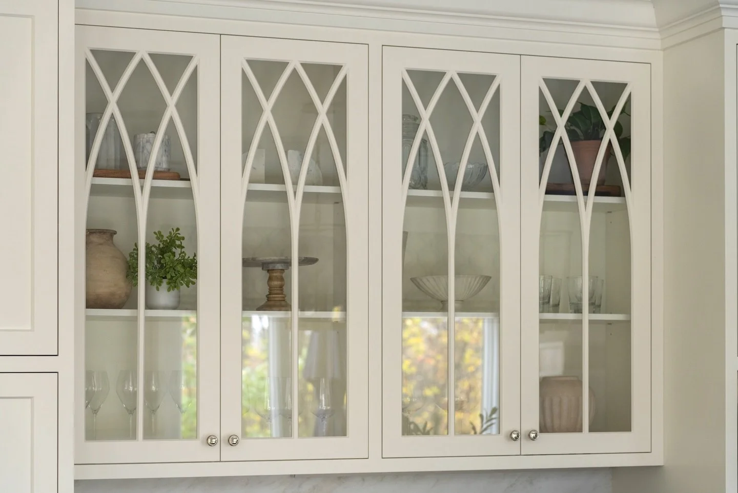 Gothic arch mullions bring an architectural element to glass-front cabinetry while still allowing for a curated display. A detail like this adds character and a sense of timelessness to the space 🪟🤍

Design: @colorandcrownid 
Builder: @revivalcraft