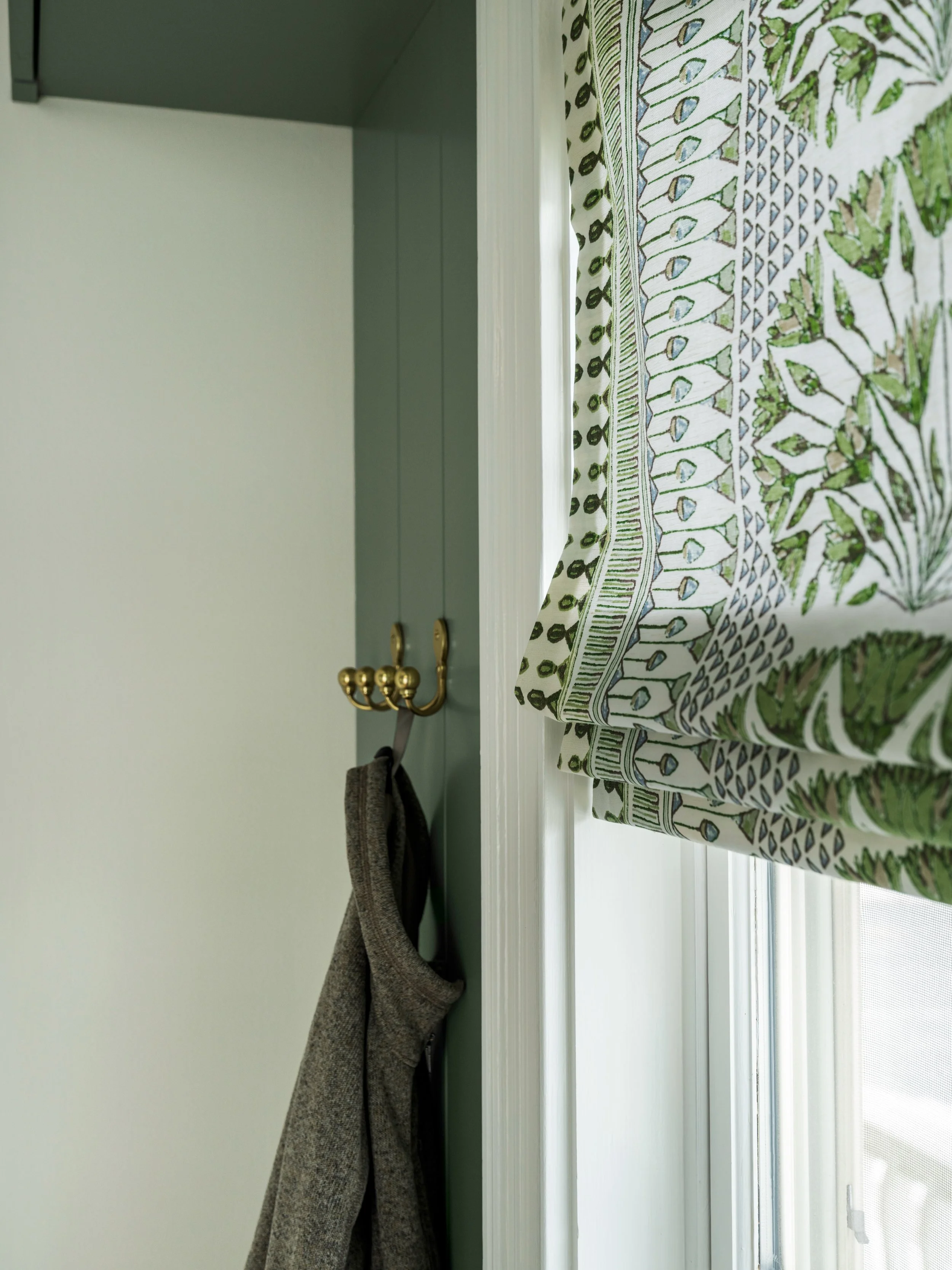 A Roman shade is a great way to add personality without the heaviness of full-length drapes. Choosing a bold pattern for this window helps draw your eye in while tying together the surrounding green cabinetry 🪟

Design: @colorandcrownid 
Cabinetry: 