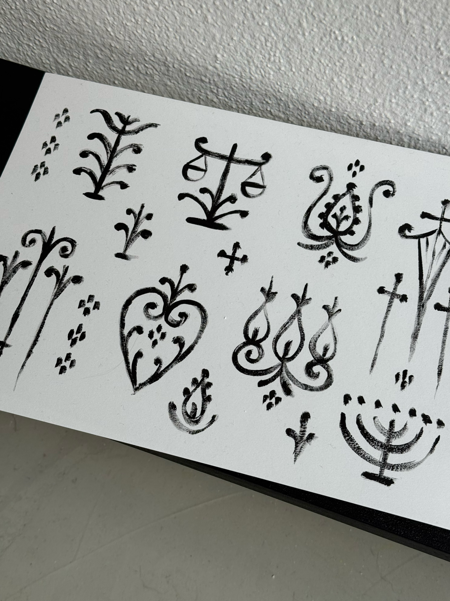 Dessin noir sur papier blanc représentant différentes motifs de styles végétaux et floraux.