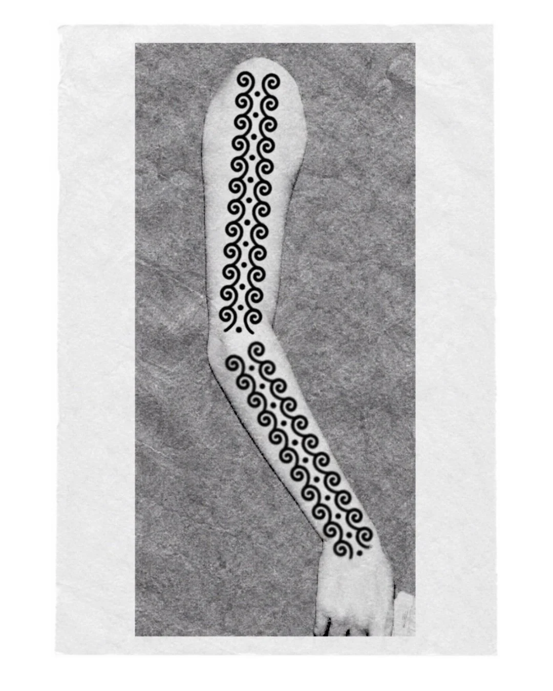 Tatouage noir et blanc d'un motif géométrique de spirales sur le long bras d'une personne.