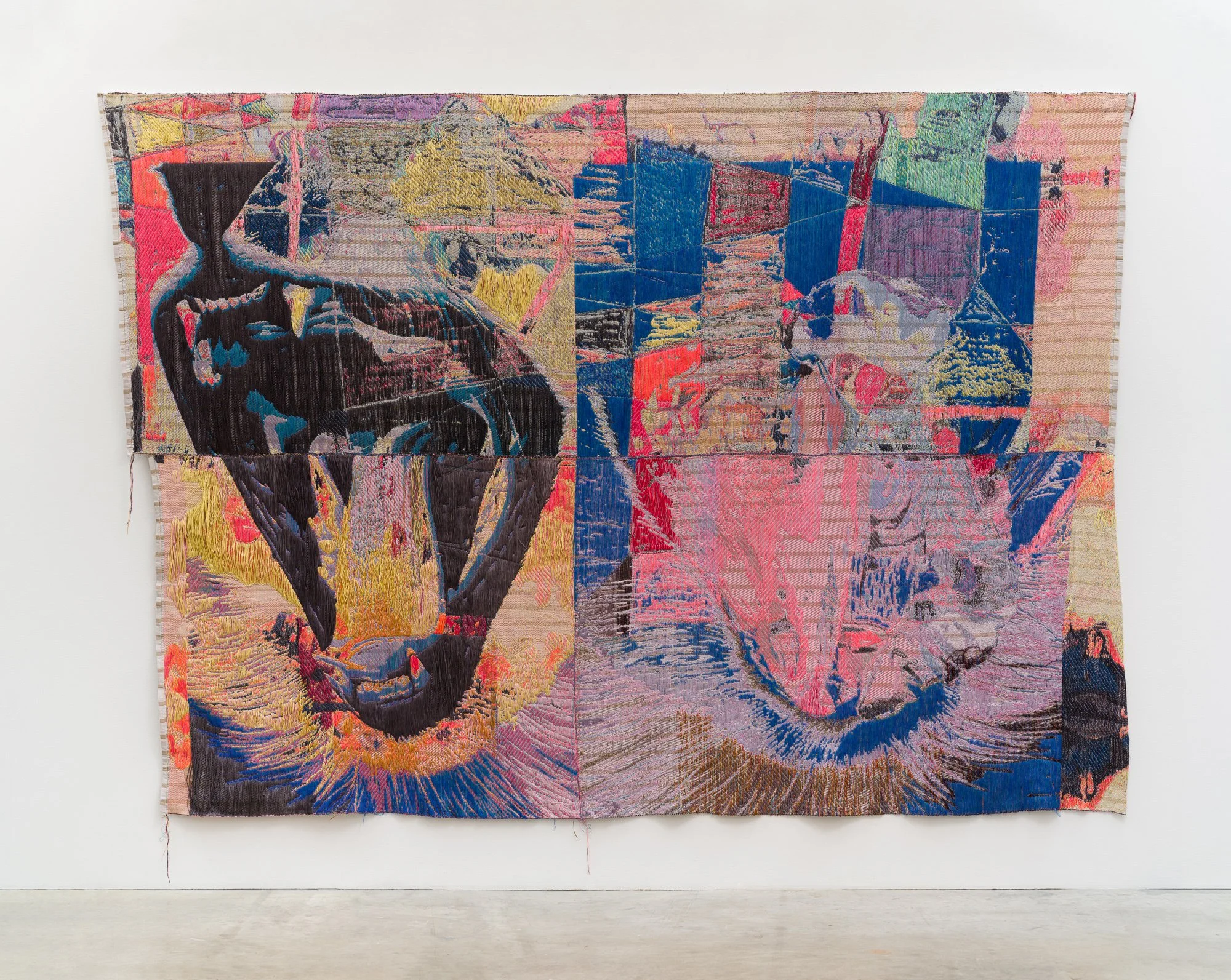 A colorful textile artwork hanging on a white wall, featuring an abstract design with various colors, shapes, and stitched patterns.