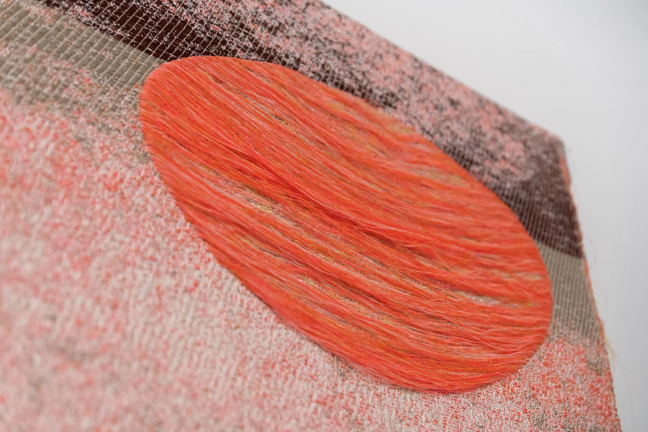 Close-up of a textured fabric surface with a prominent orange-painted wooden stick resting on it.