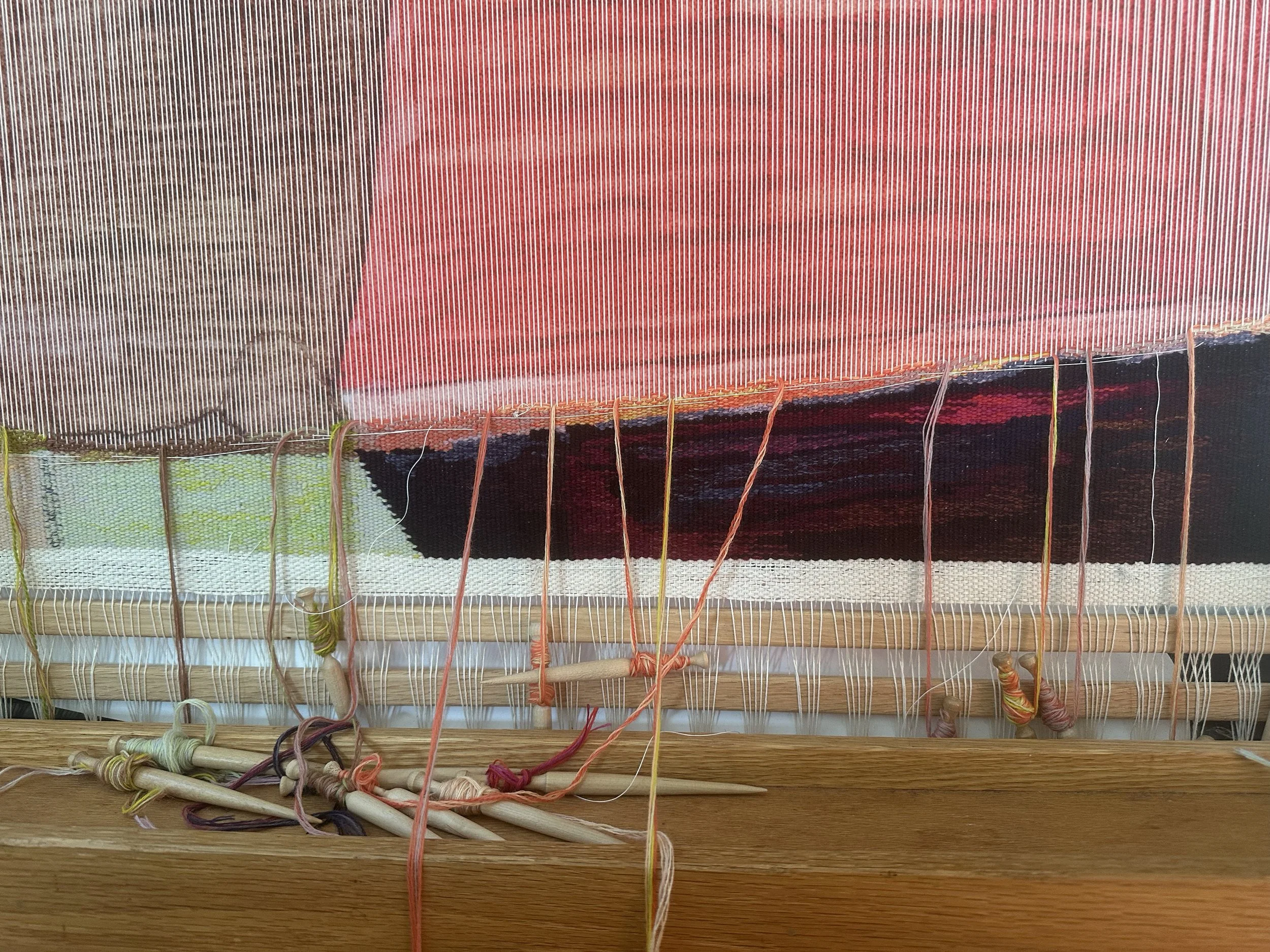 A weaving loom with colorful yarns in the process of being woven.