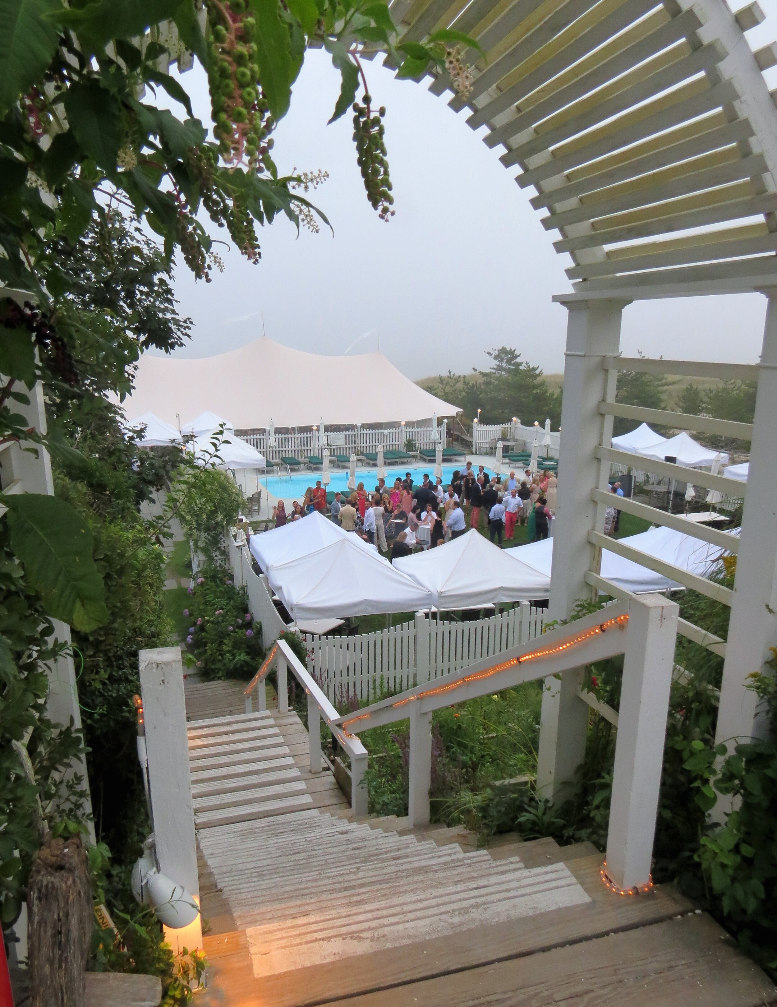 A wedding gathering near a beach, featuring a pool and tents