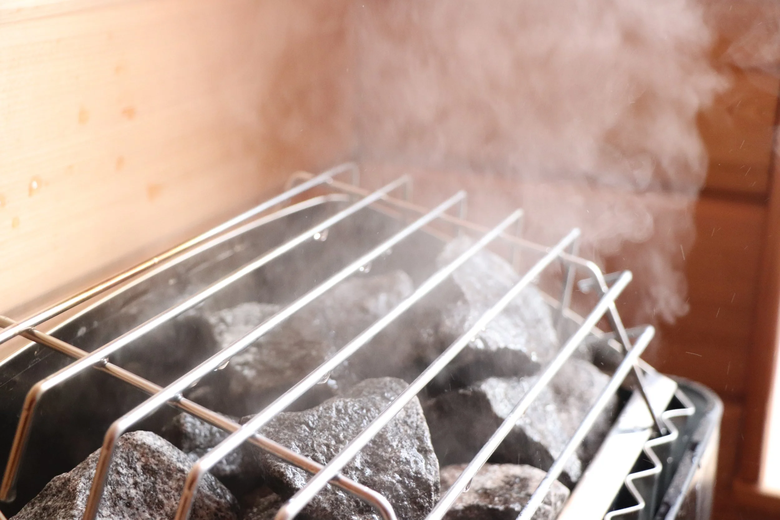 Hot stones on a grill with steam or smoke rising from them.