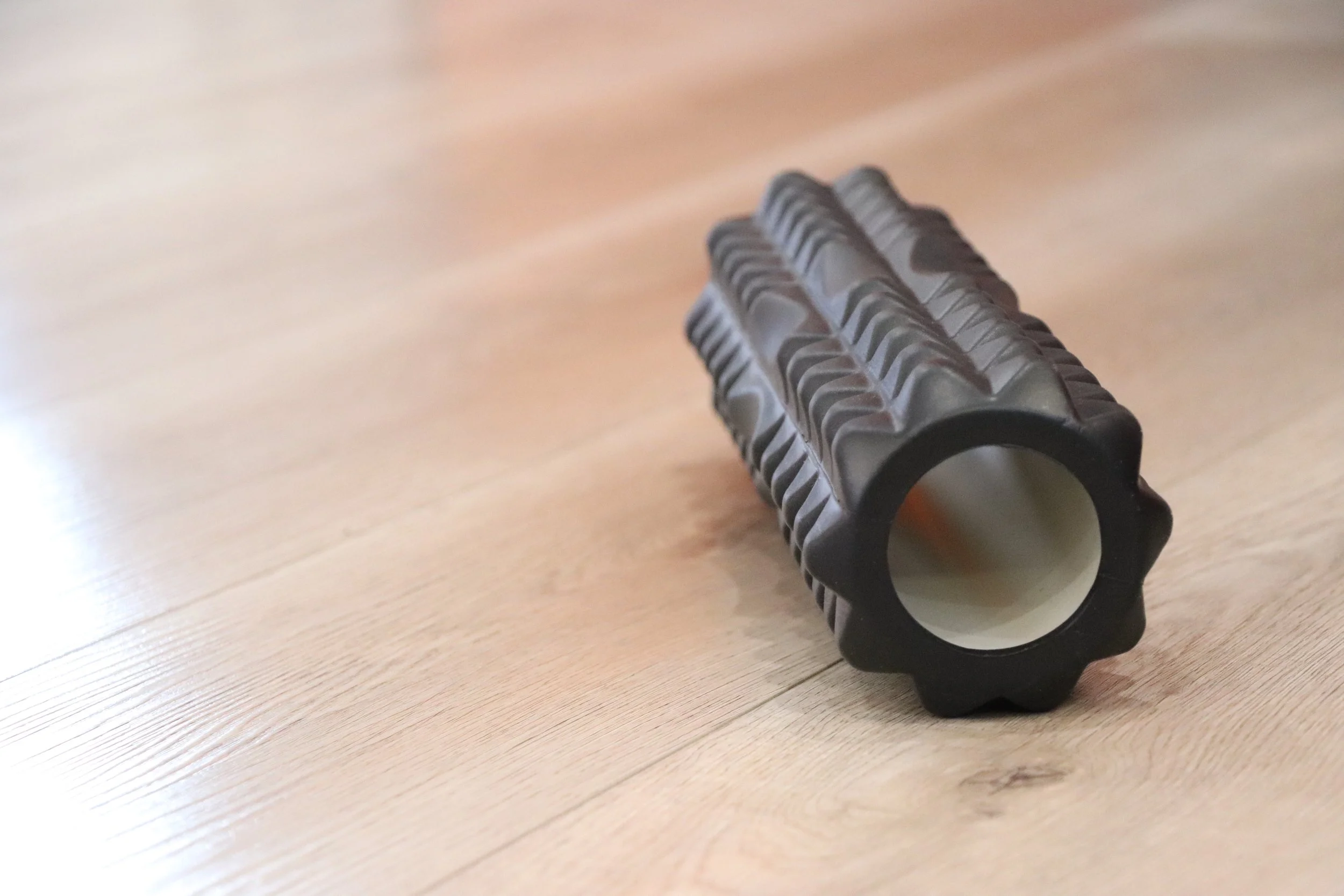 A black and gray cylindrical object with ridges, lying on a wooden surface.