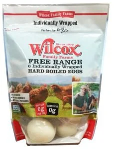 Pack of Wilcox Family Farms large hard-boiled eggs, six individually wrapped, in a plastic bag with label showing eggs and a woman holding a basket of eggs outside.