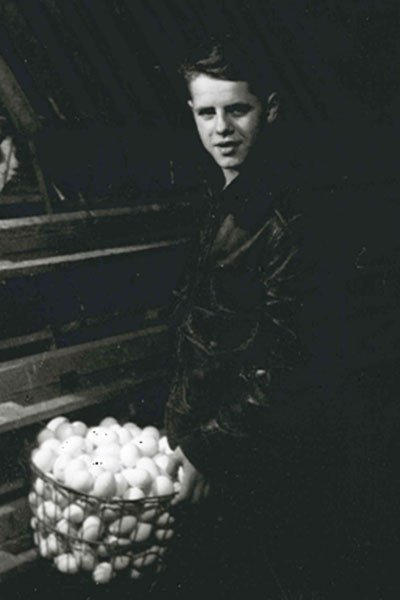 A person standing next to a basket of eggs in a dark environment.