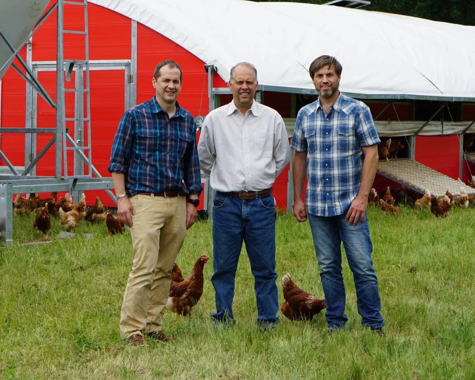 Andy, Chris, and Brent Wilcox, Wilcox family members who run the farm, standing together on the Wilcox Farms property.
