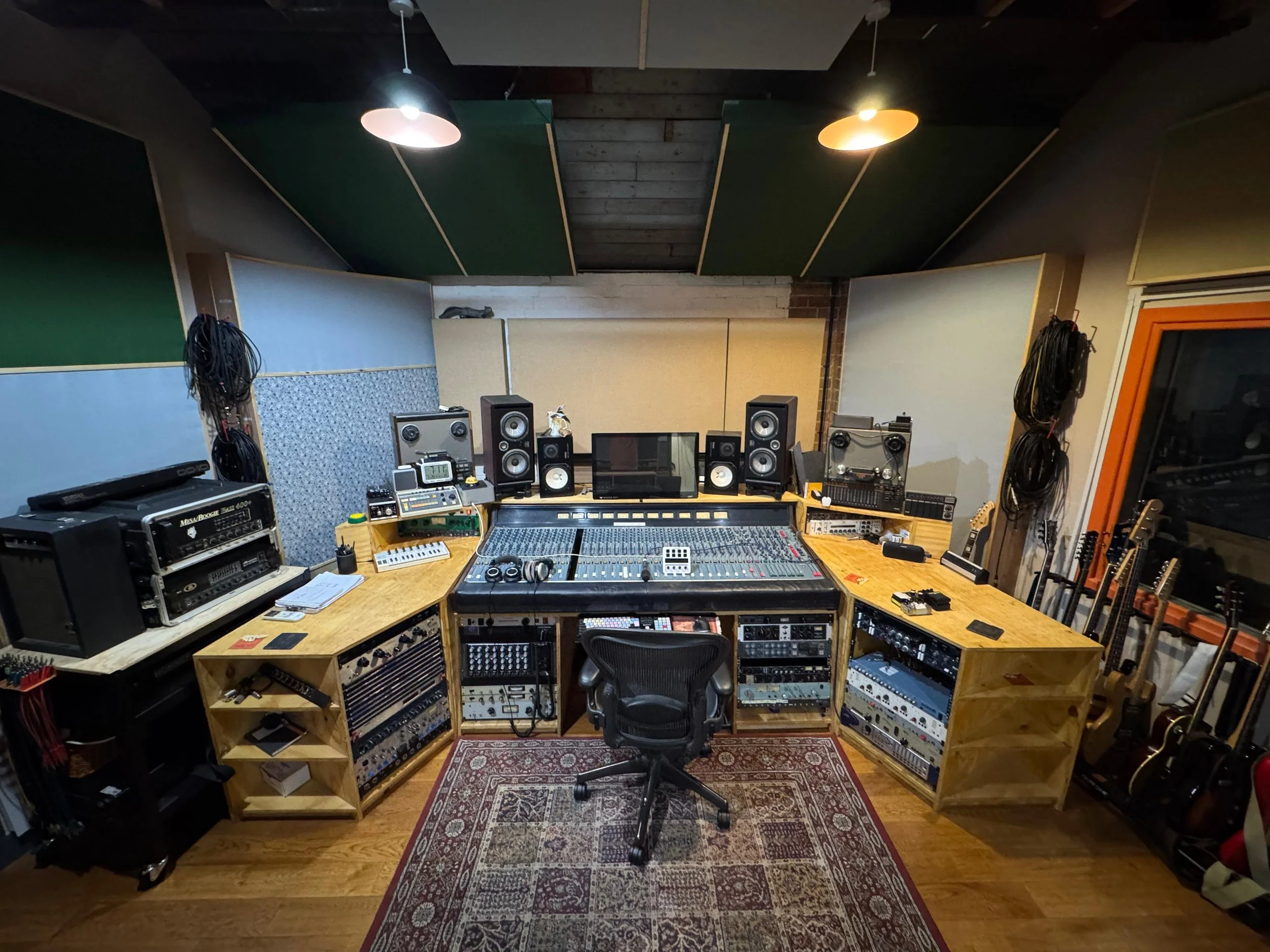 Sound recording studio with mixing console, speakers, guitars, and equipment racks. JT Soar Nottingham