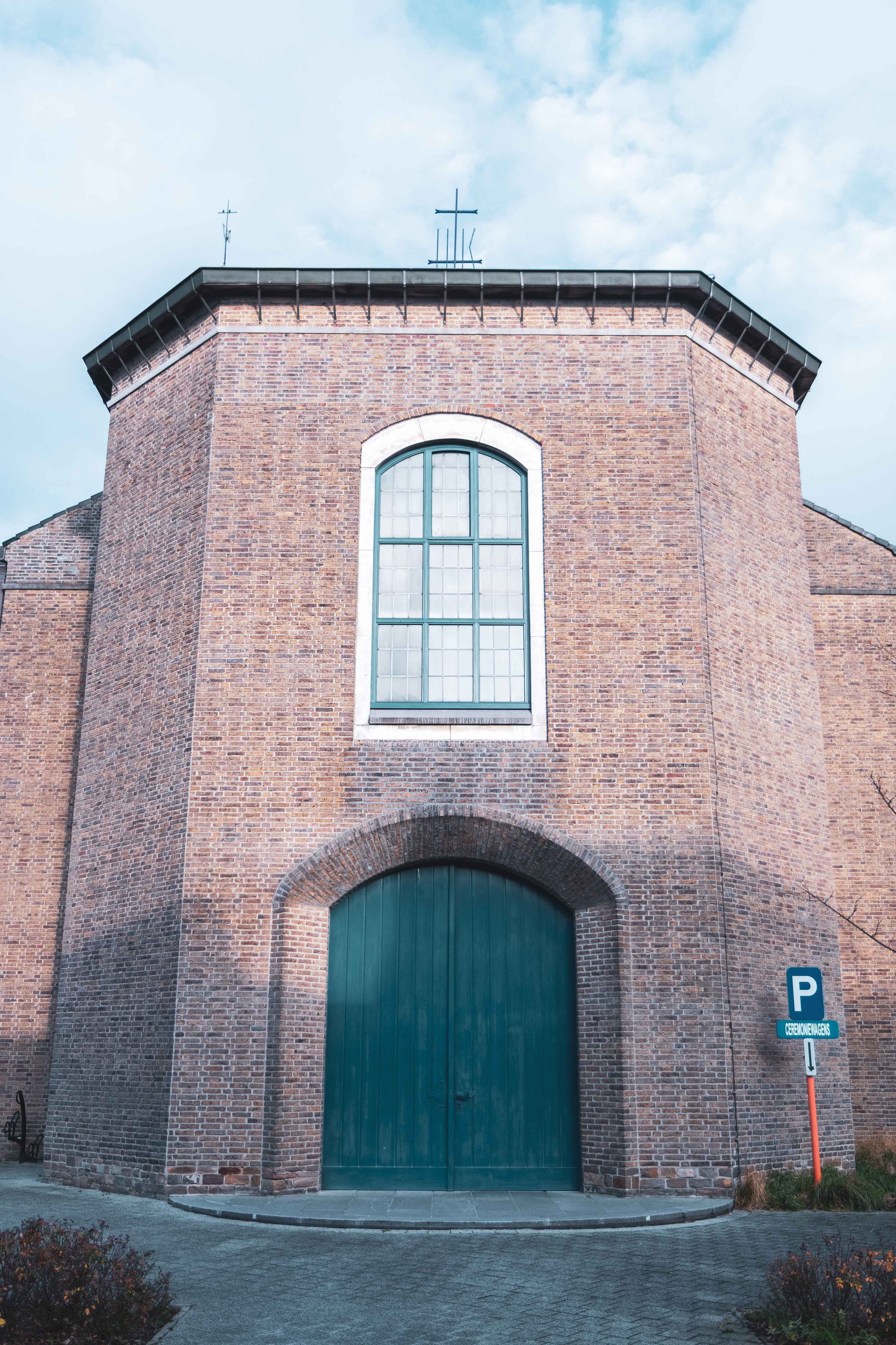 Een grote bakstenen muur met een grote groene poort en een grote raam erboven.