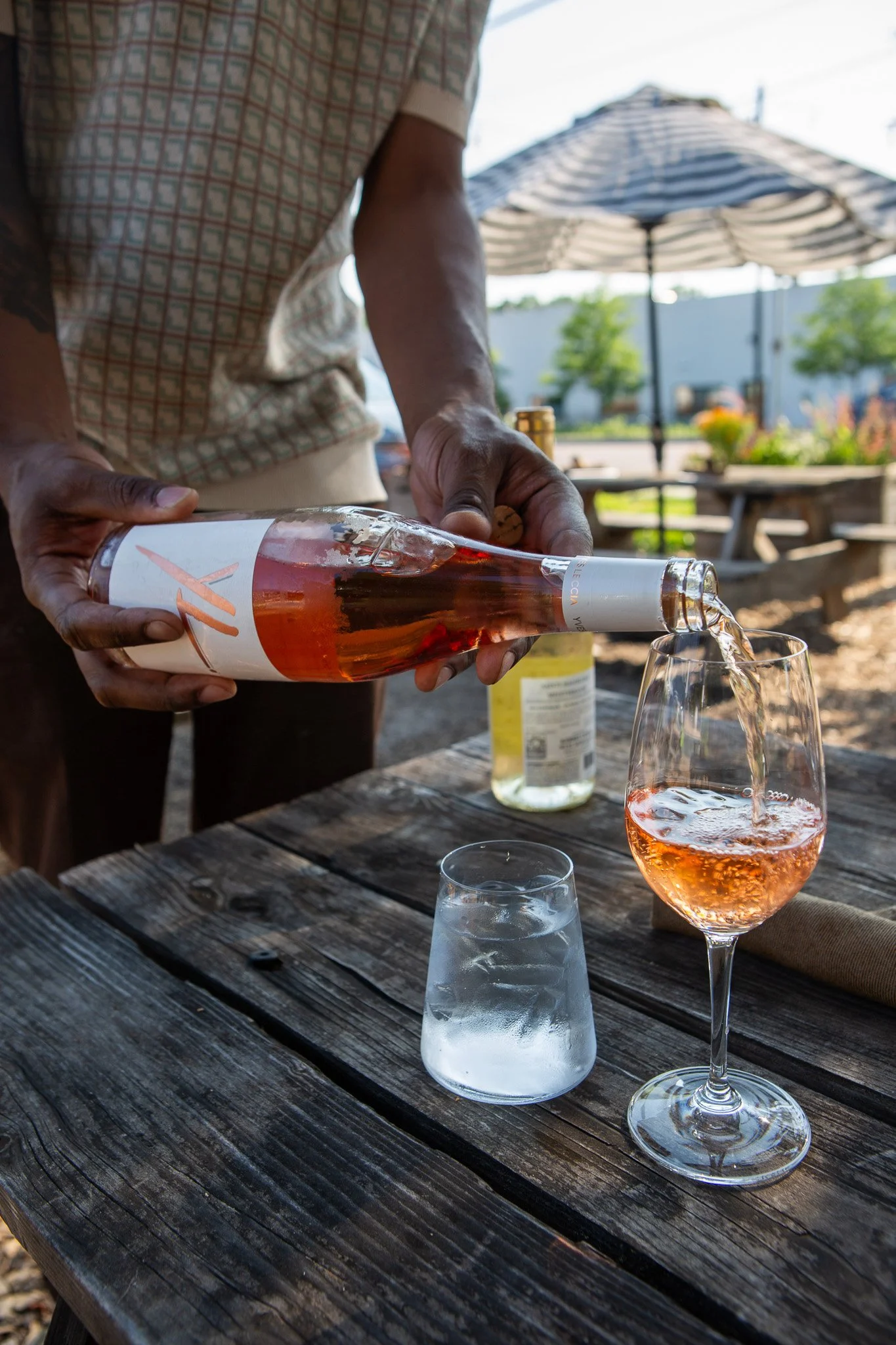 Rosé wine being poured into a glass at an outdoor picnic table