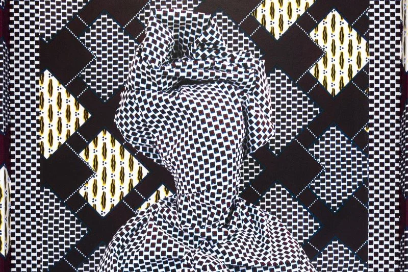 A black, white, and yellow geometric patterned fabric on a surface, with a crumpled piece of matching fabric placed on top.