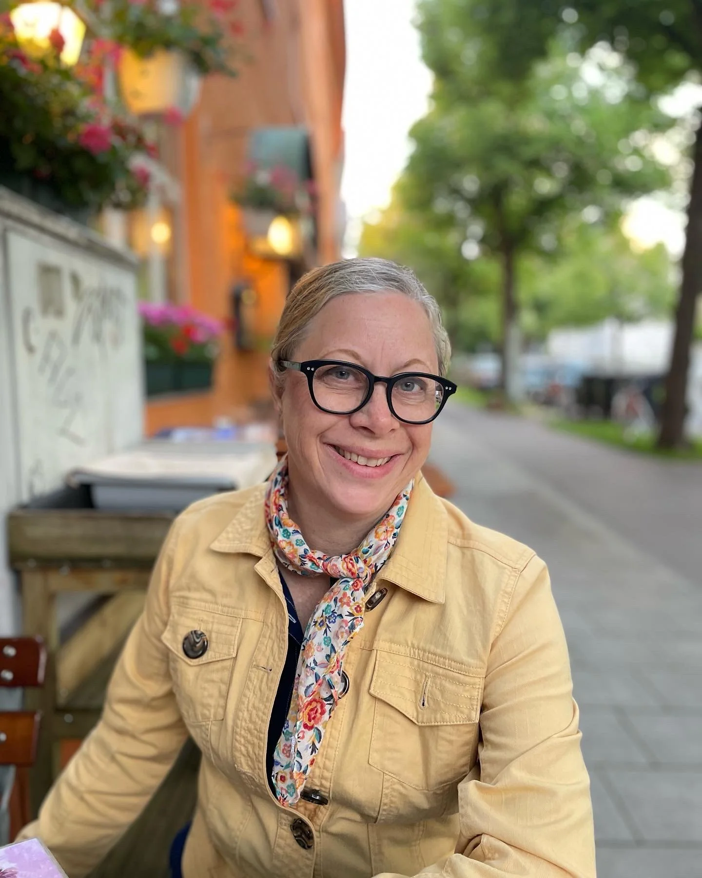 Author Julie Dieterich Pappas smiles wearing a yellow jacket