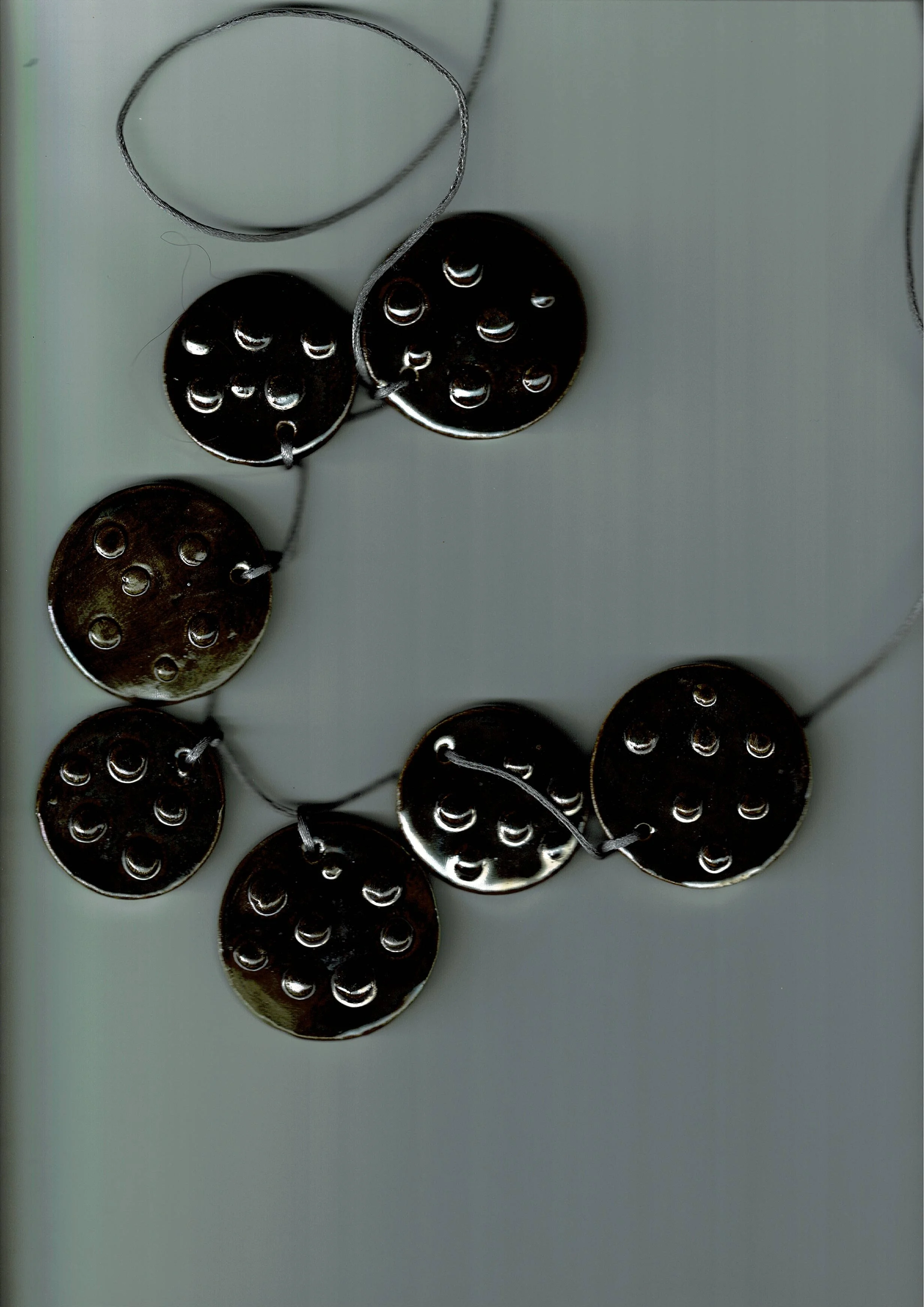 Une guirlande de boutons noirs attachés avec un fil gris.