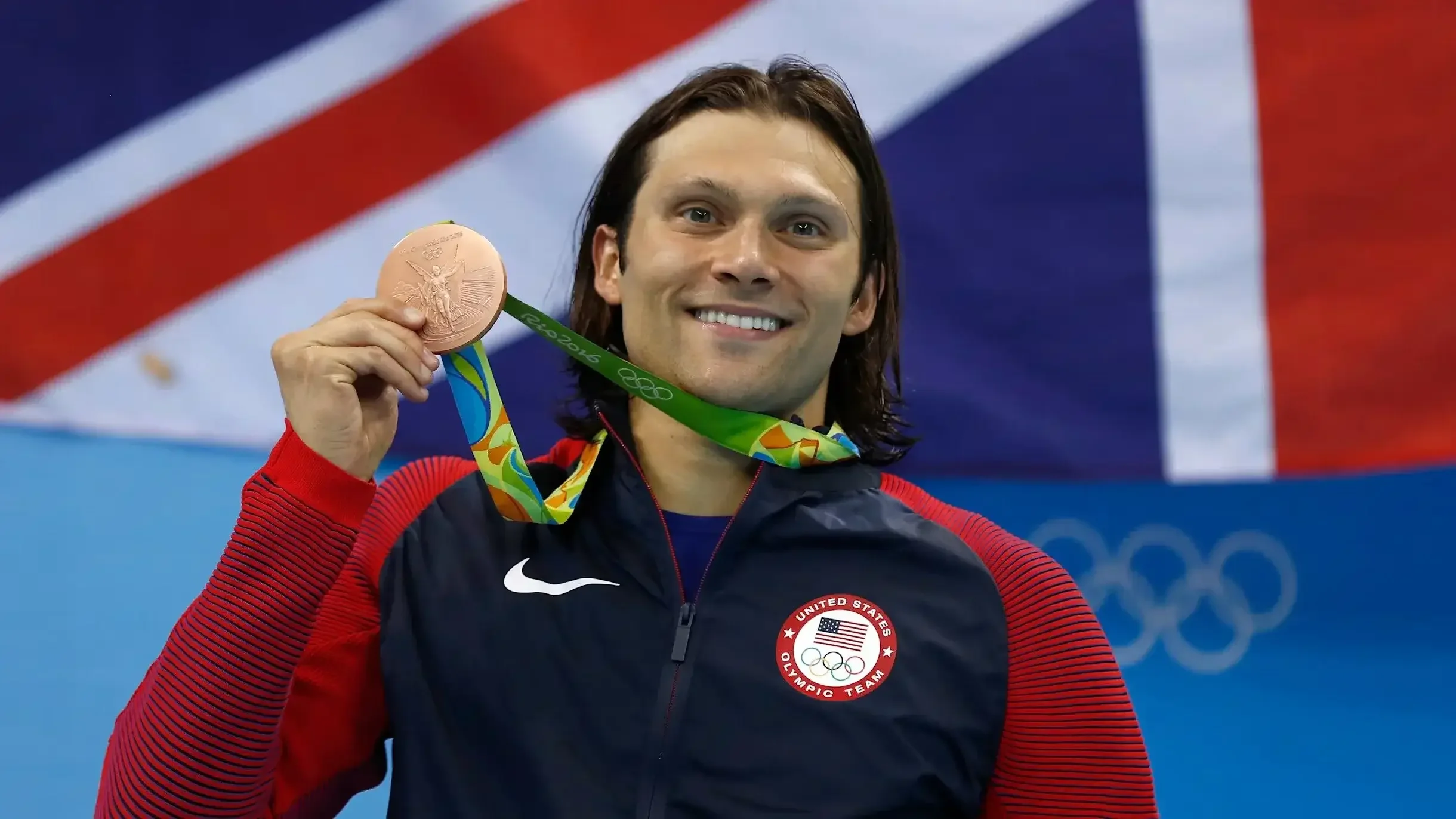 Olympic medalist Cody Miller holding medal, guest coach for Eagle Swim Camps