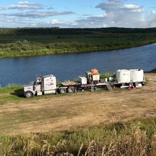 A trailer with an orange mixing tank on the back