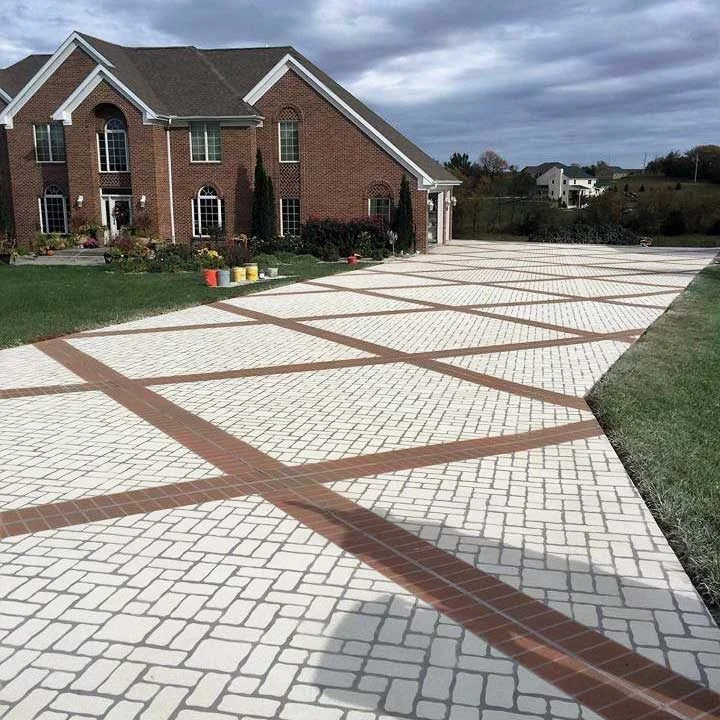 Brick house with a patterned decorative concrete driveway leading up to it across a grassy lawn.