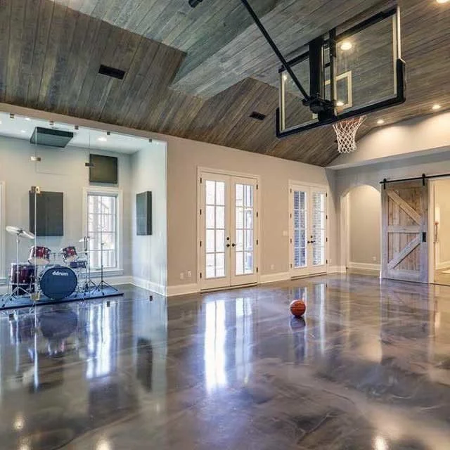 Indoor home basketball court with a polished metallic reflector floor, hoop and large glass doors.