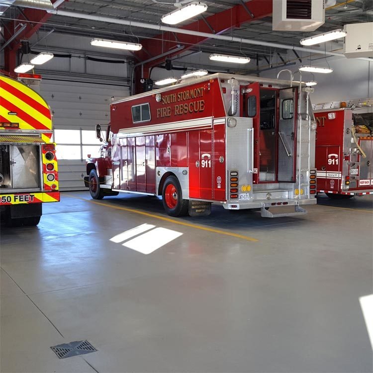 Red fire rescue truck inside a fire station apparatus bay with yellow floor lines and an epoxy floor coating.